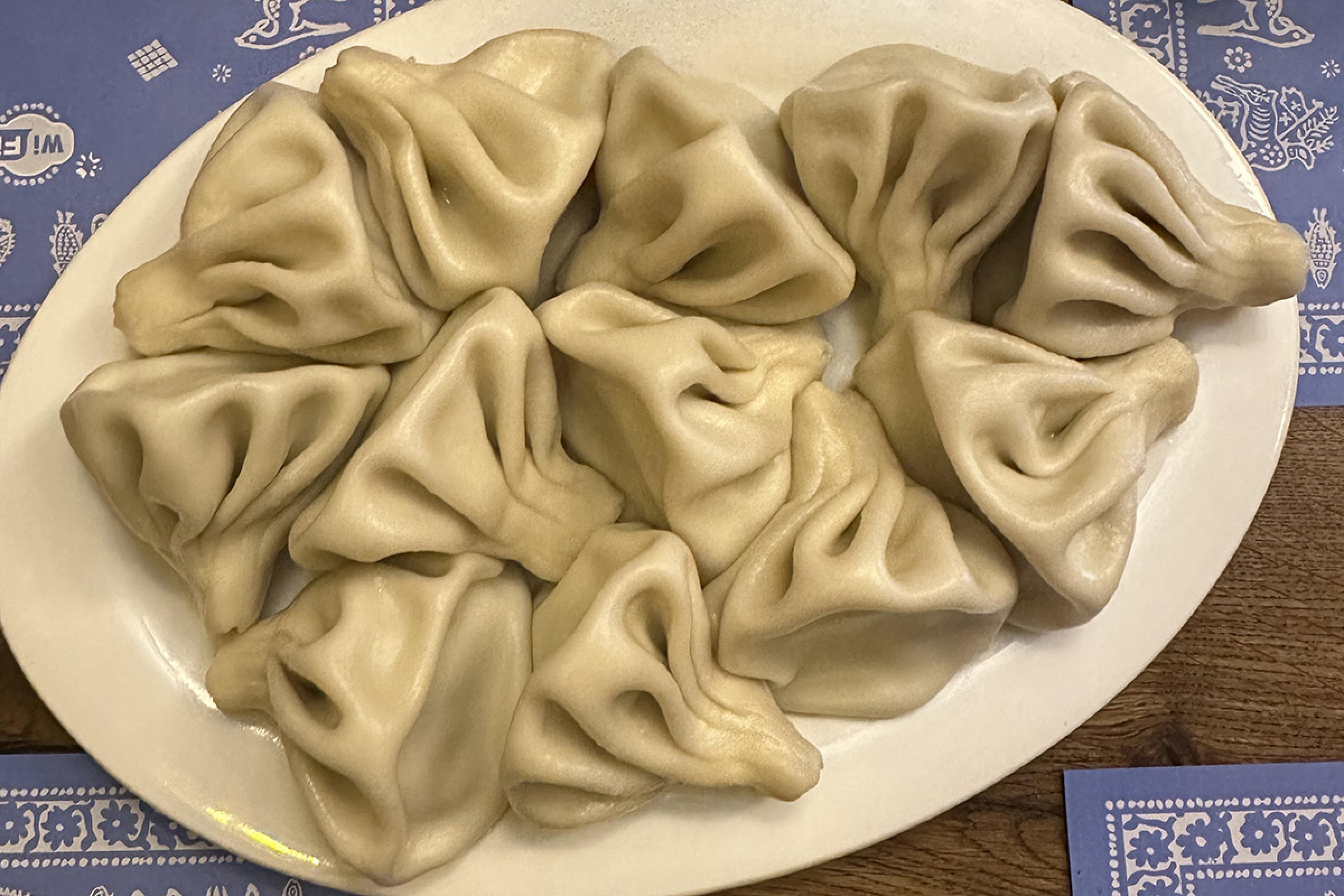 soup dumplings on a white plate with blue and white placemats on the table