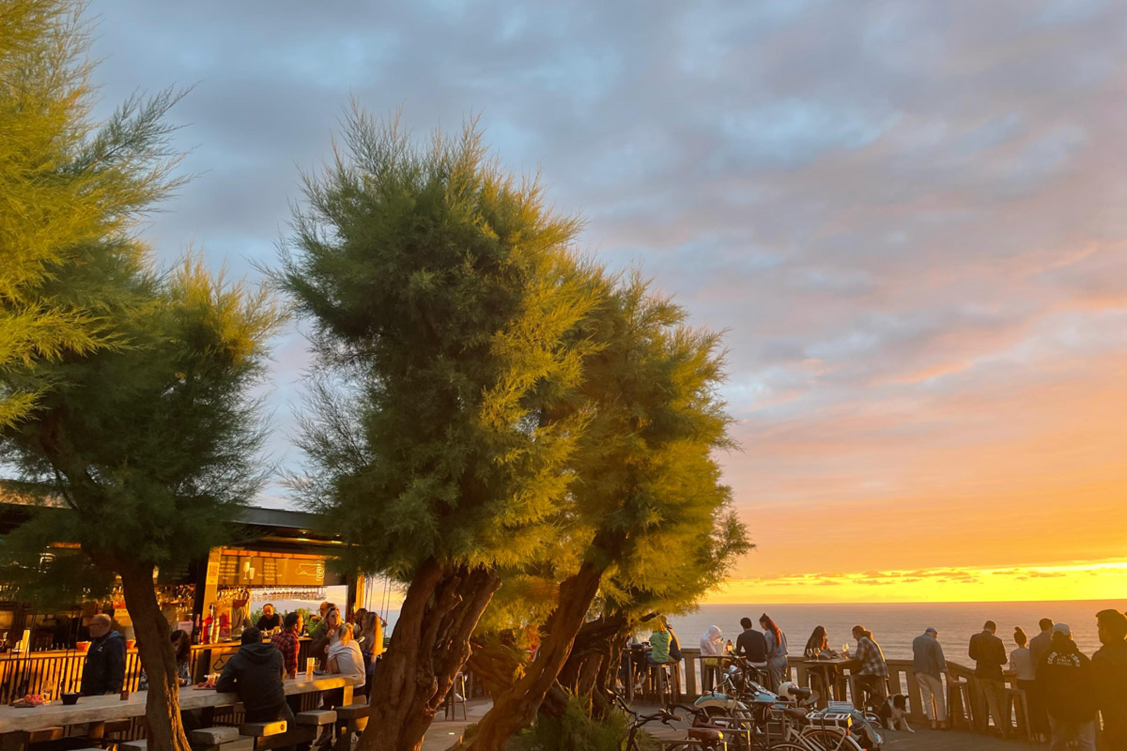 sunset view over ocean with outdoor restaurant in foreground