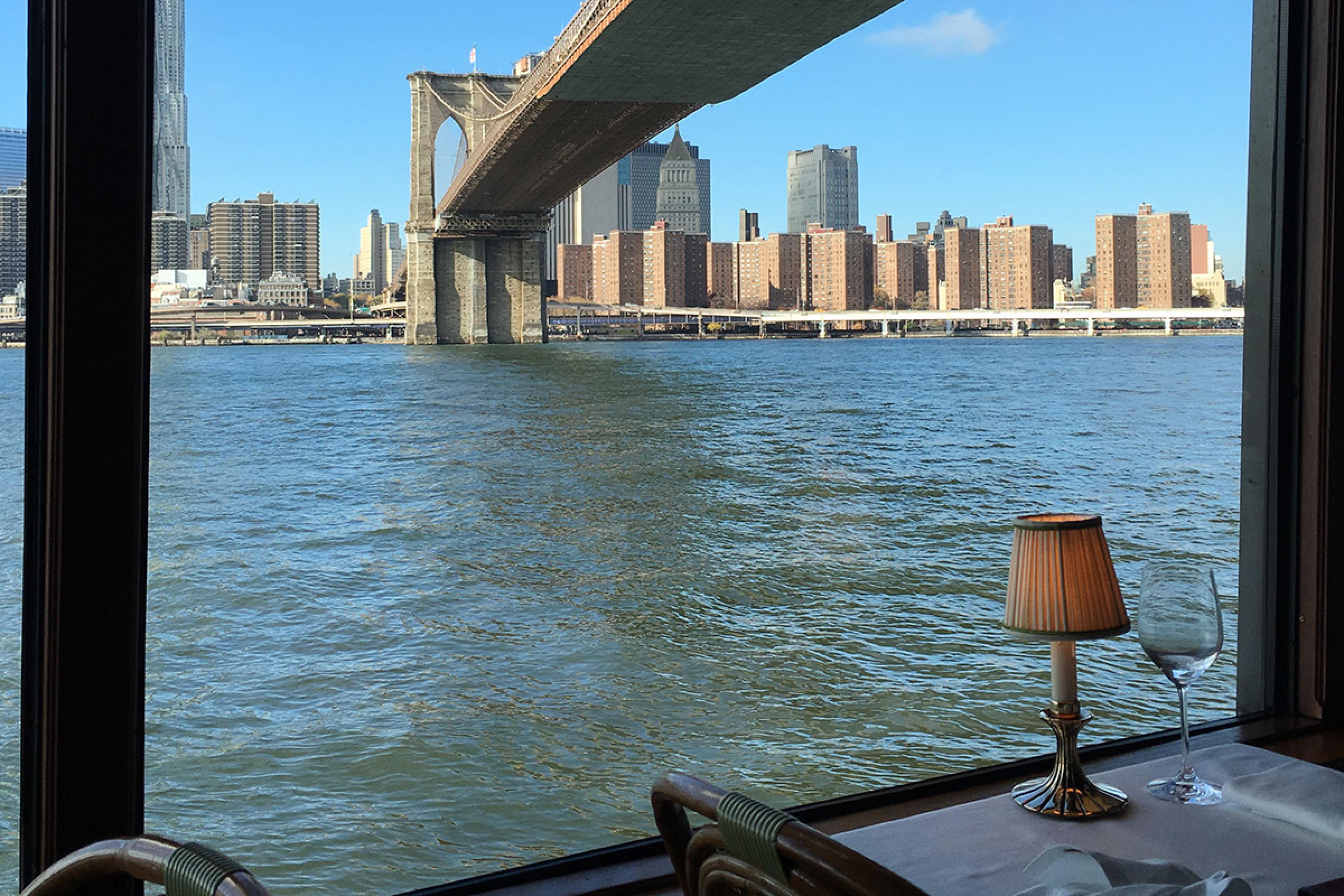table at waterfront restaurant under brooklyn bridge looking out to manhattan