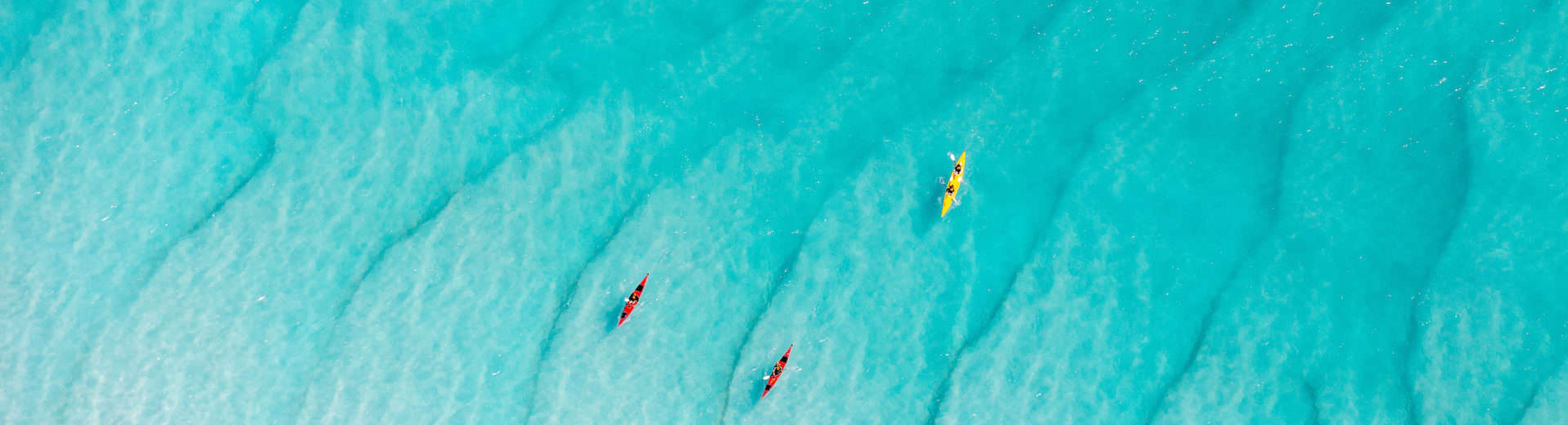 aerial view of 3 kayaks in clear blue ocean