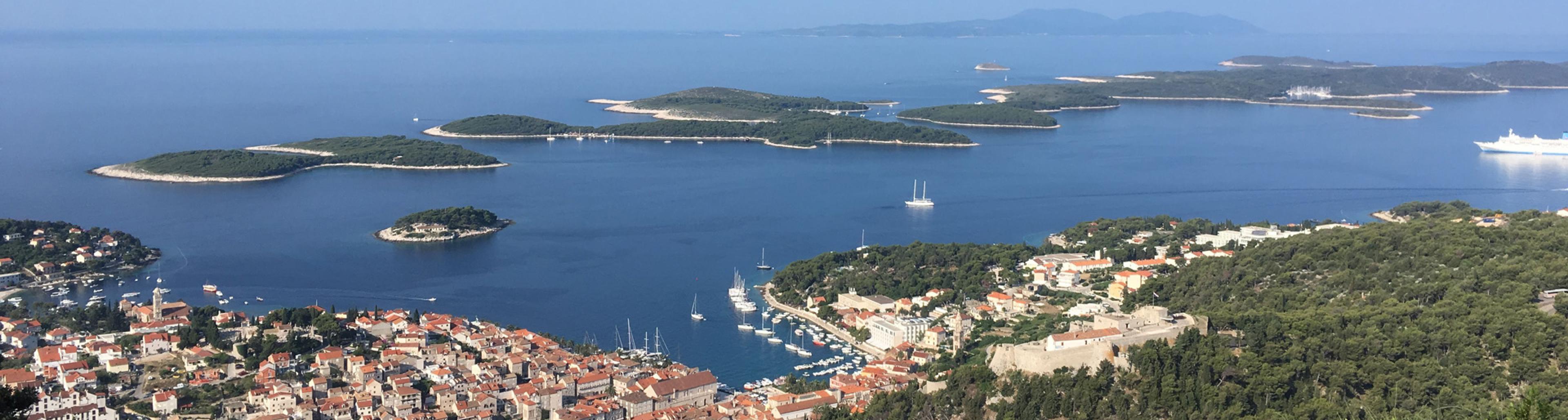 view over town of hvar croatia with tree-topped islands in blue sea in background