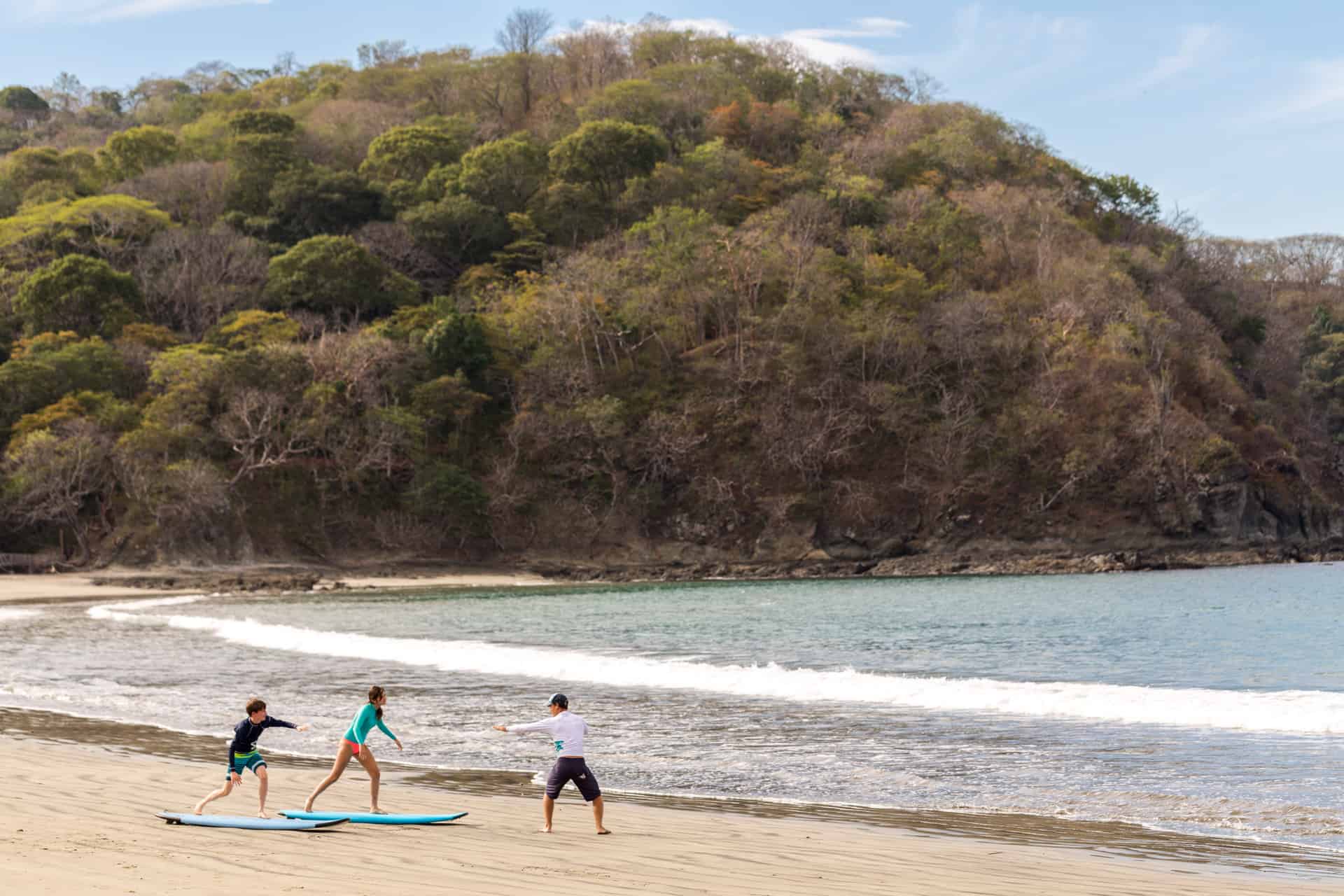 Three people practicing surfing on beach near Four Seasons Costa Rica