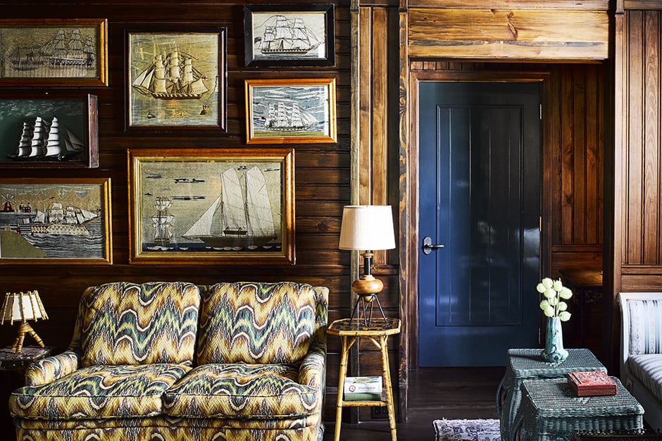 Couch with sailboat paintings on wall above at Greydon House in Nantucket