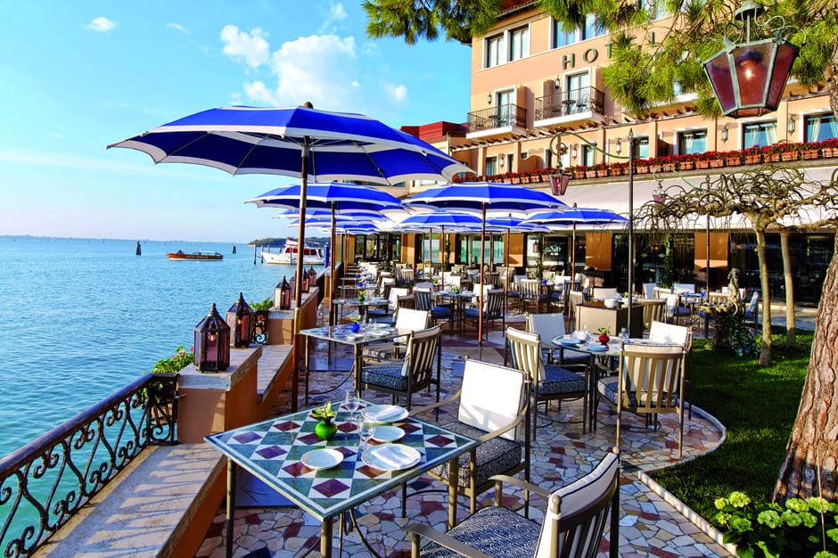 Outdoor patio with tables beside water at Belmond Hotel Cipriani in Venice
