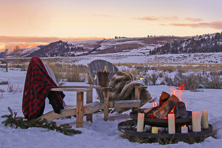 Twilight bonfire and two Adirondack chairs in the snow outside the Ranch at Rock Creek in Montana