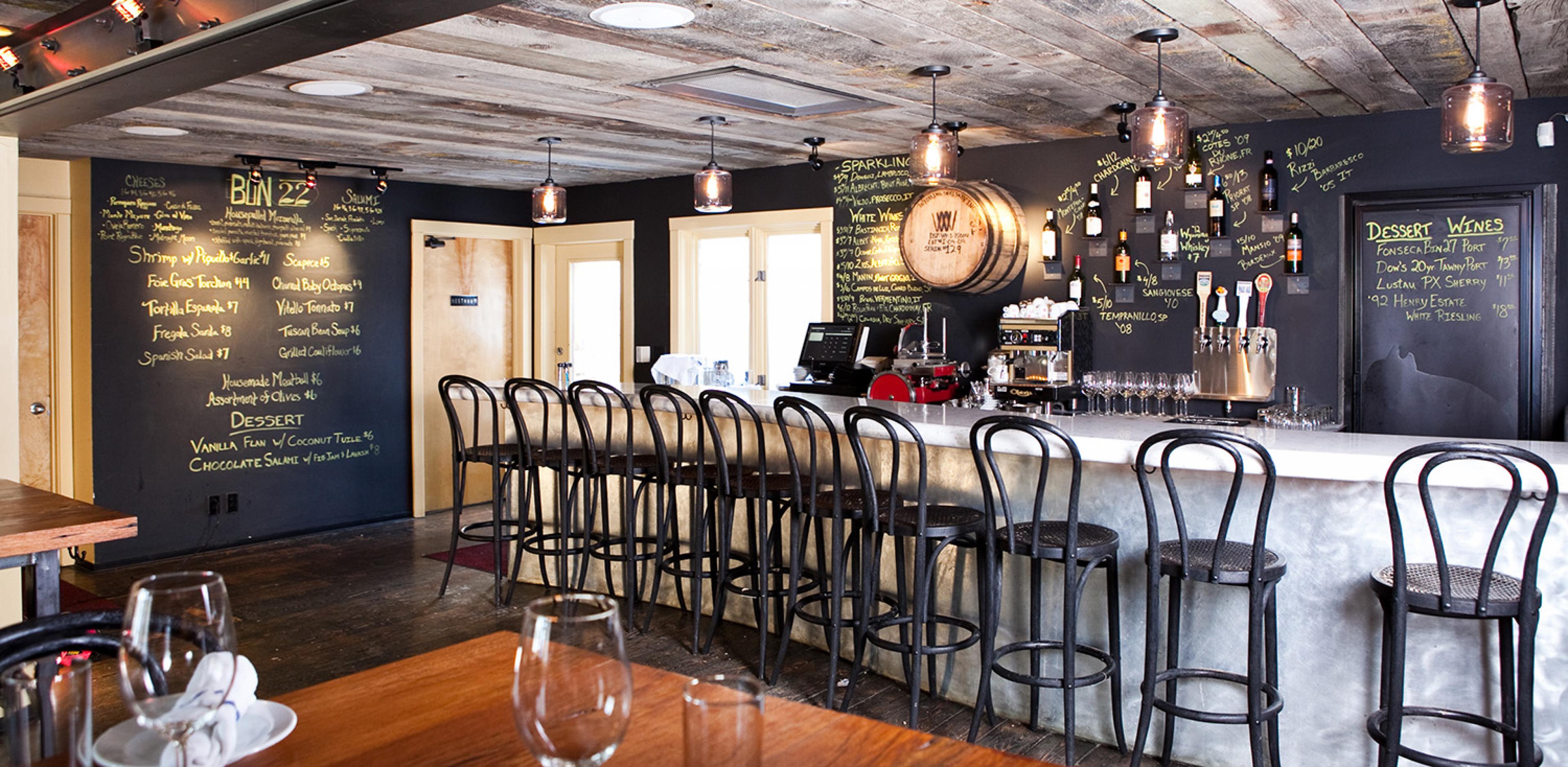bar with black stools and a chalkboard menu