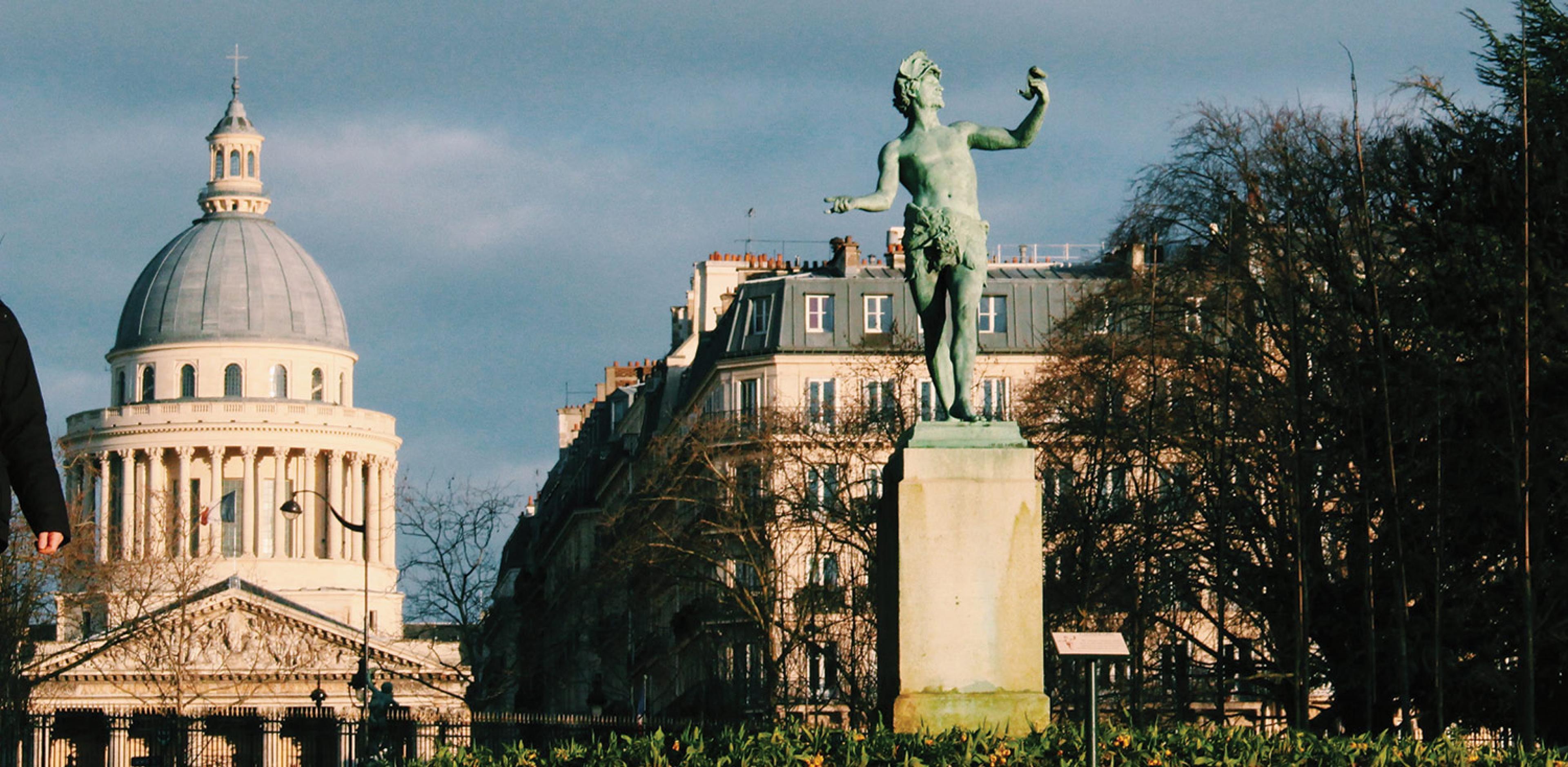 statue of greek figure in paris with pantheon building seen in background