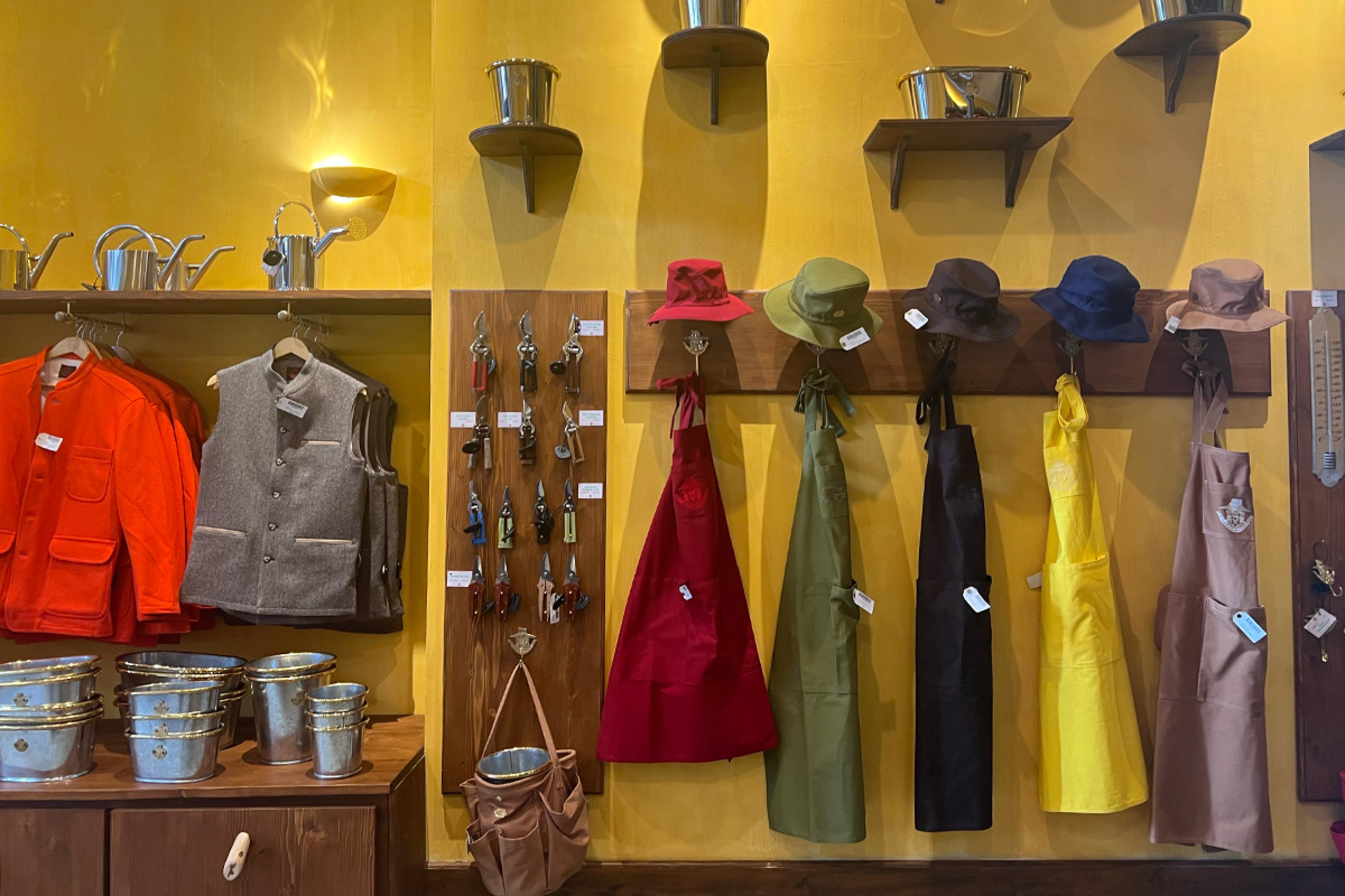 yellow wall of store with clothing and hats hanging on wooden rack