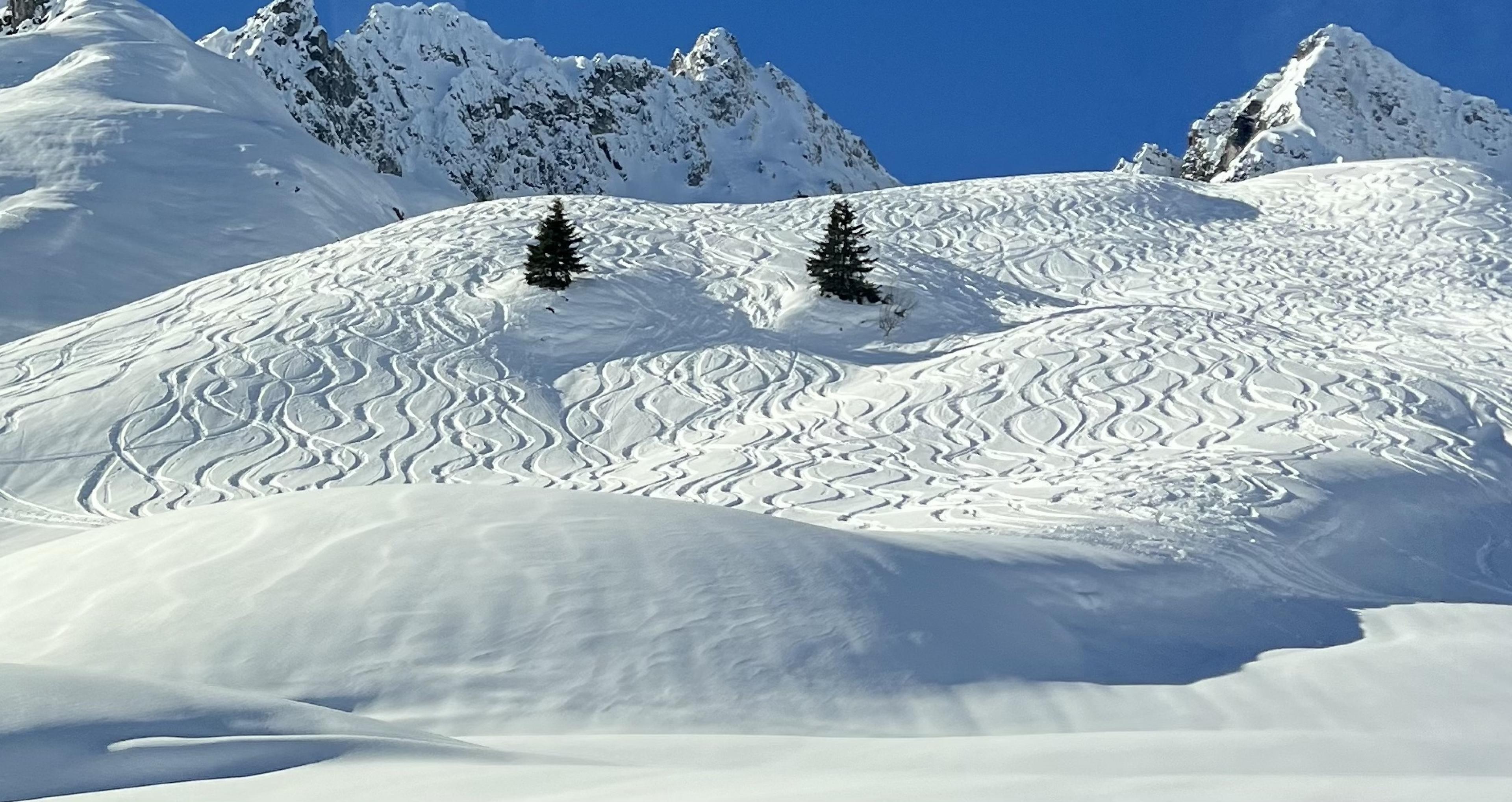 looking up at ski slopes with ski tracks on a snowy alpine mountain