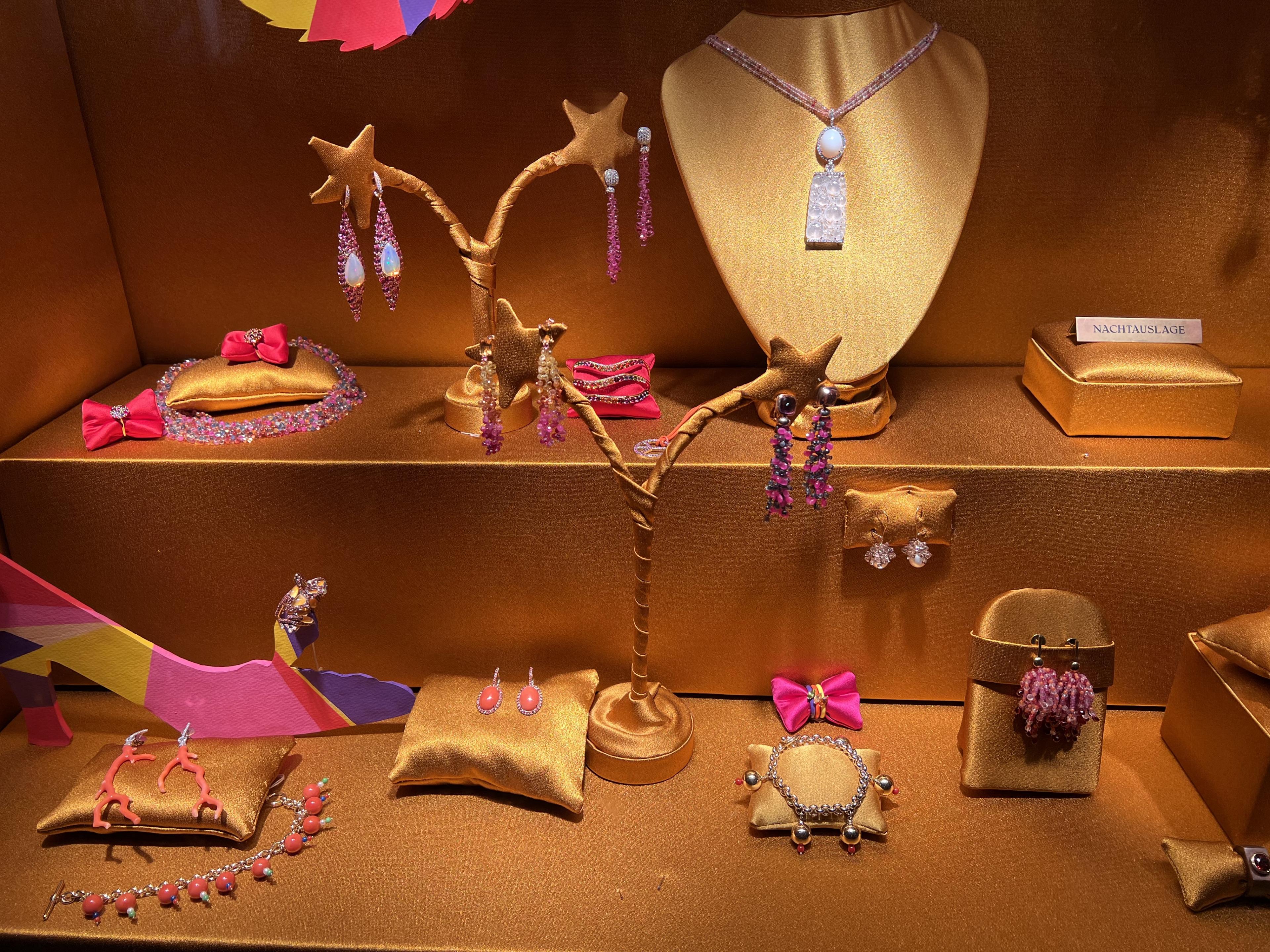 beautiful jewelry on display in a gold-fabric-lined store window