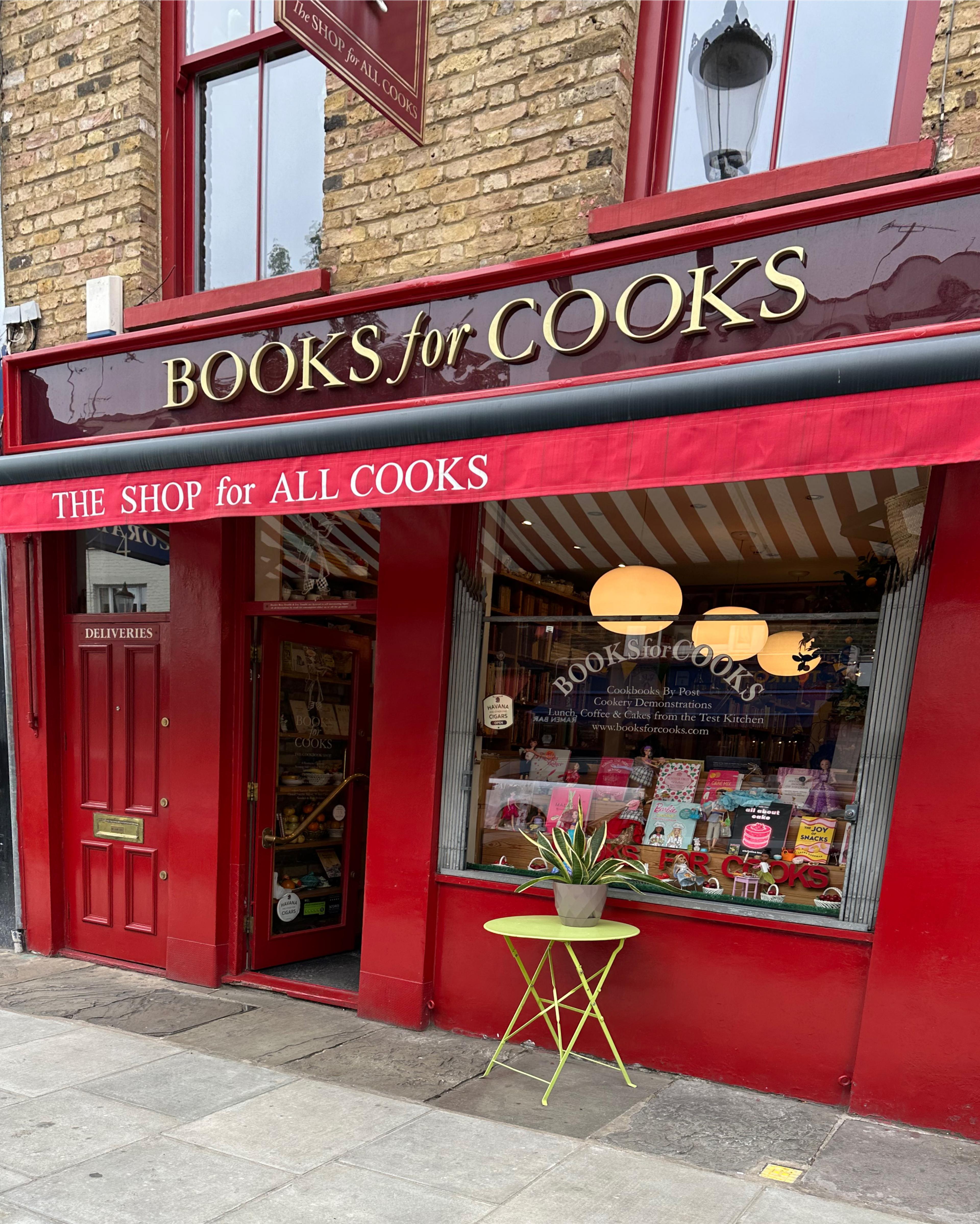 exterior of storefront in London with brick building and red sign saying Books for Cooks