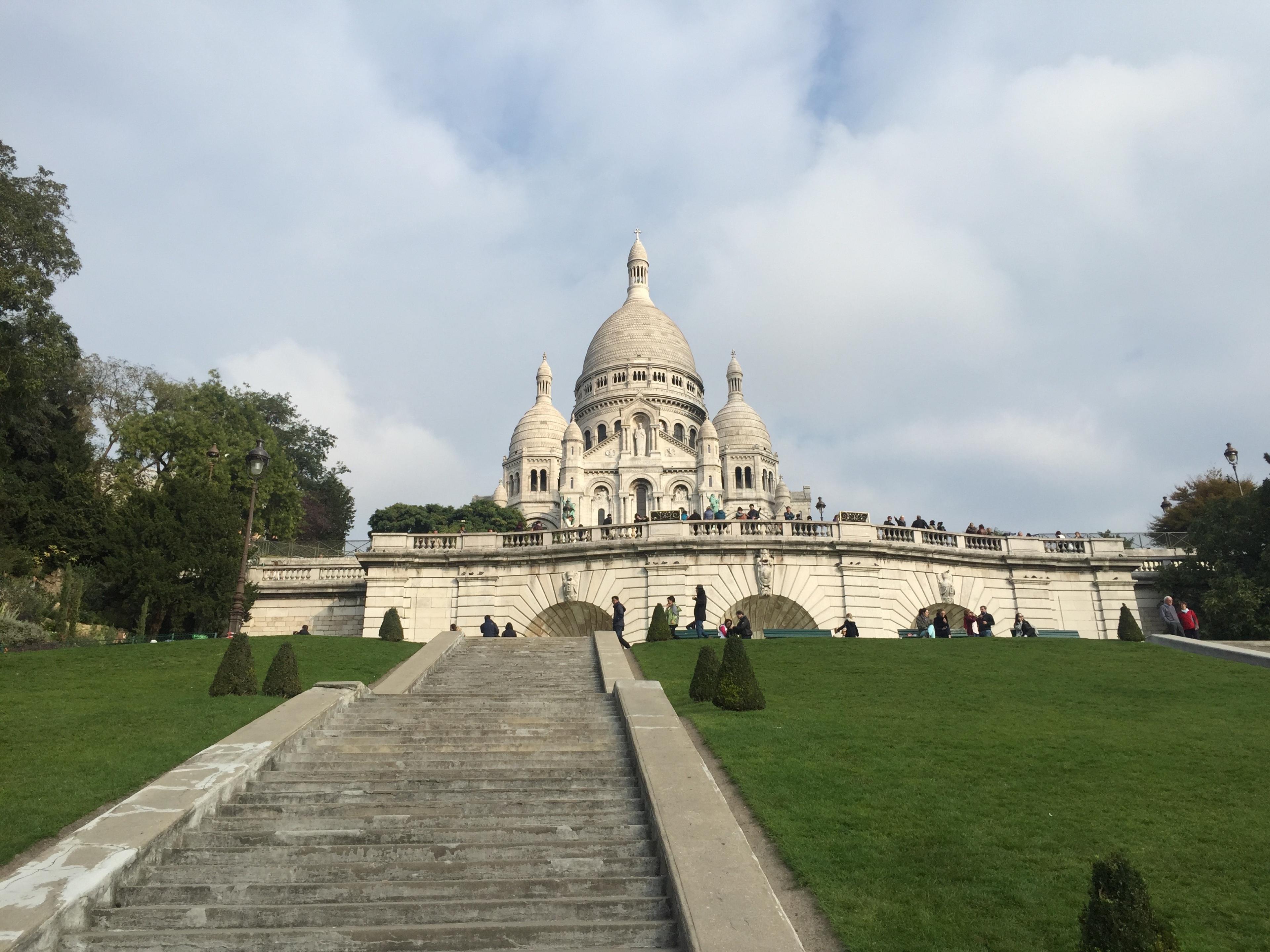 looking up at sacre coeur white church in paris from green hill