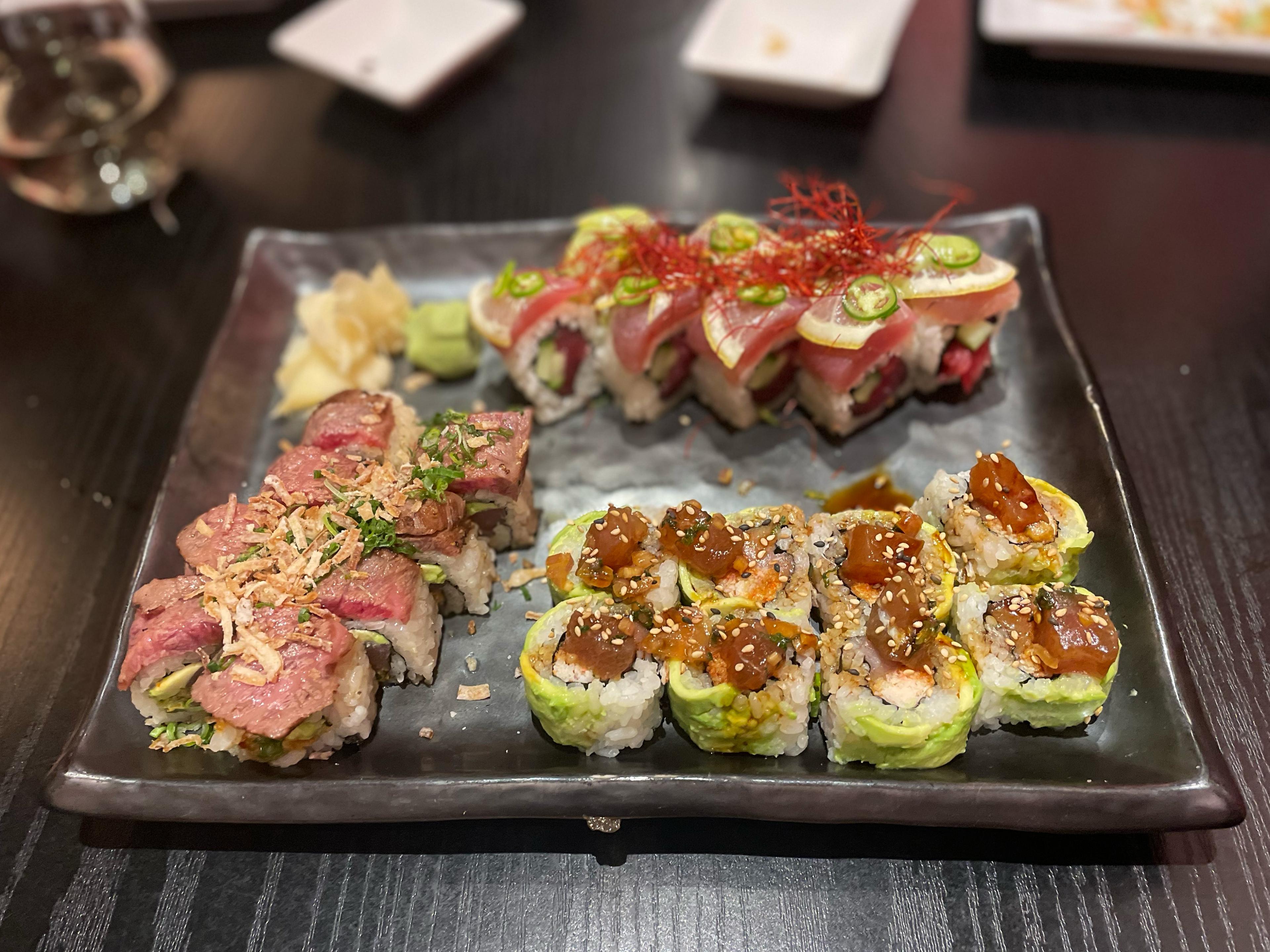 three sushi rolls on a black stone platter