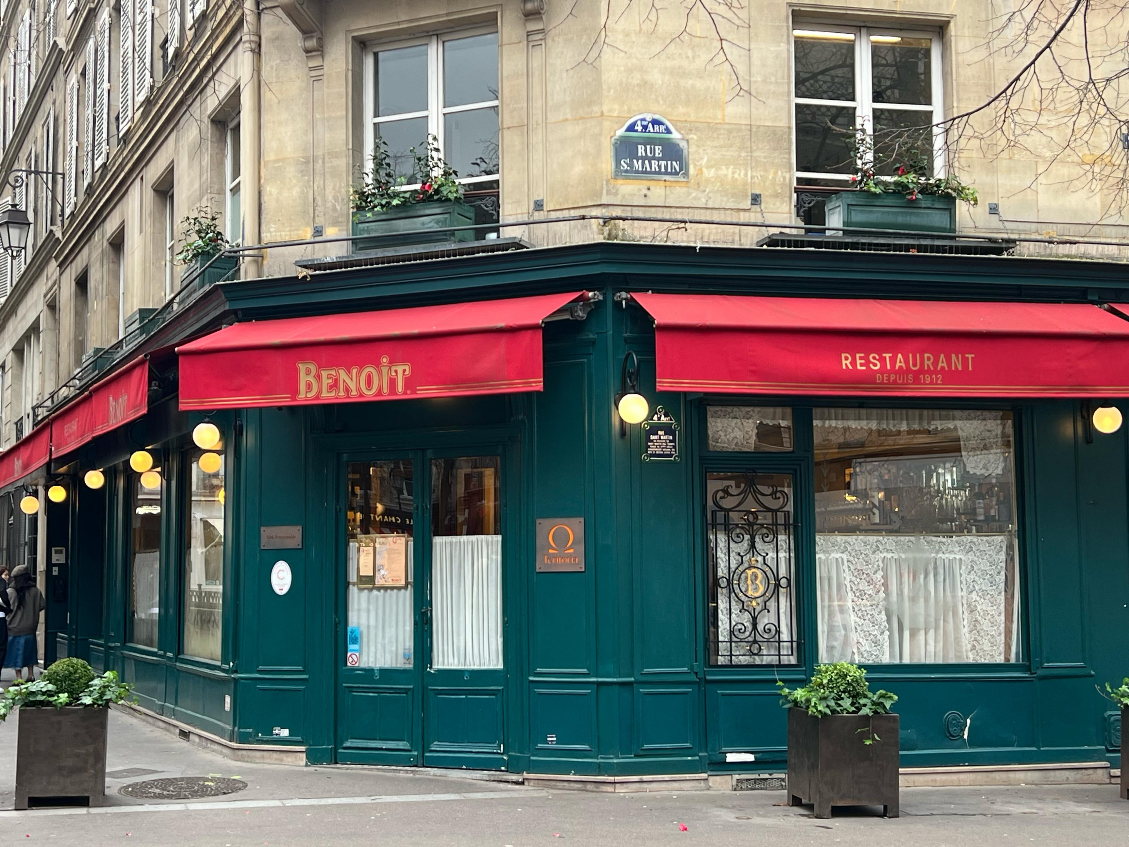 Parisian restaurant exterior with green paint and red awnings