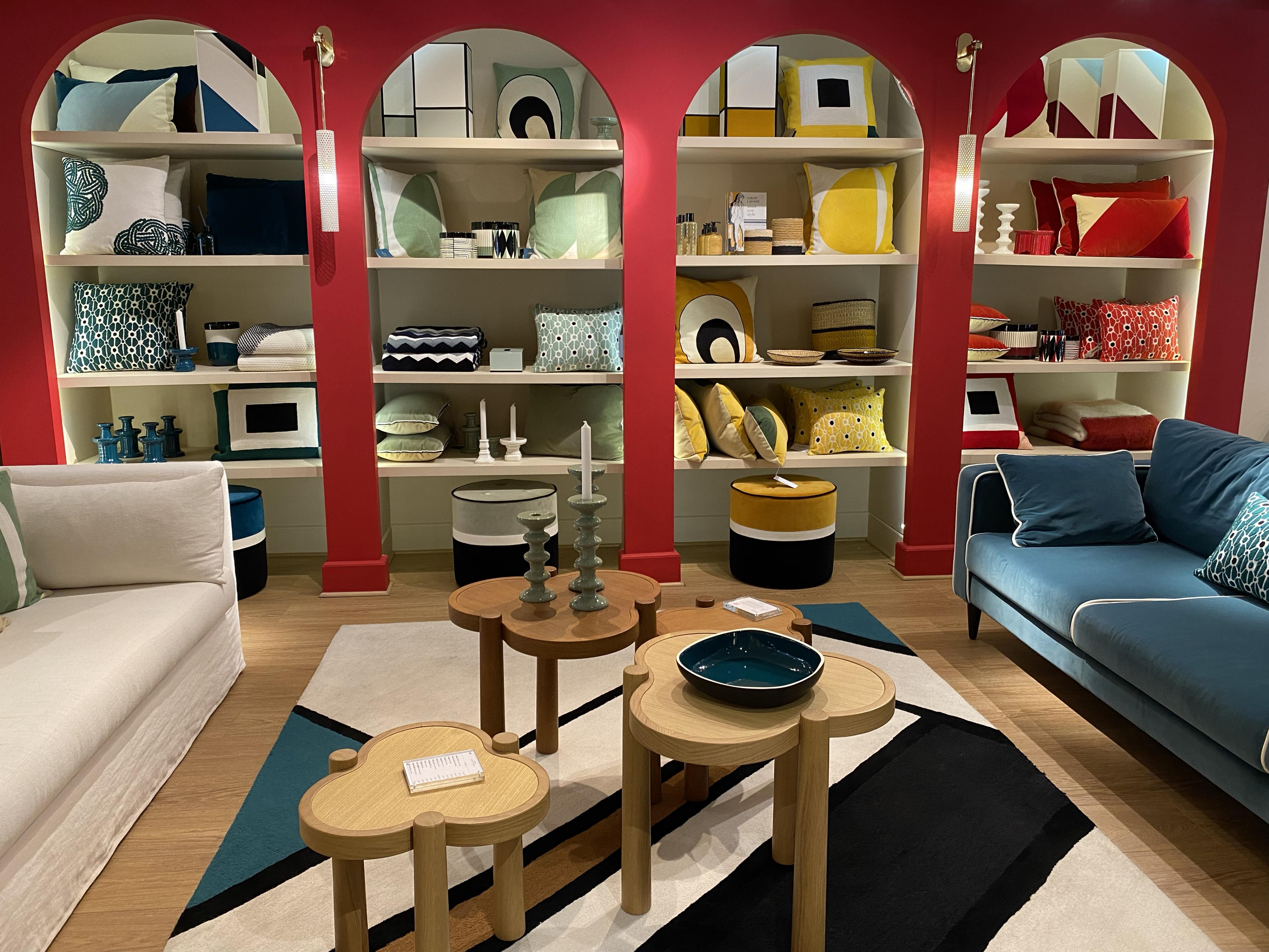 inside of a home interiors store with plates and glassware on display on built in shelves set along a red wall