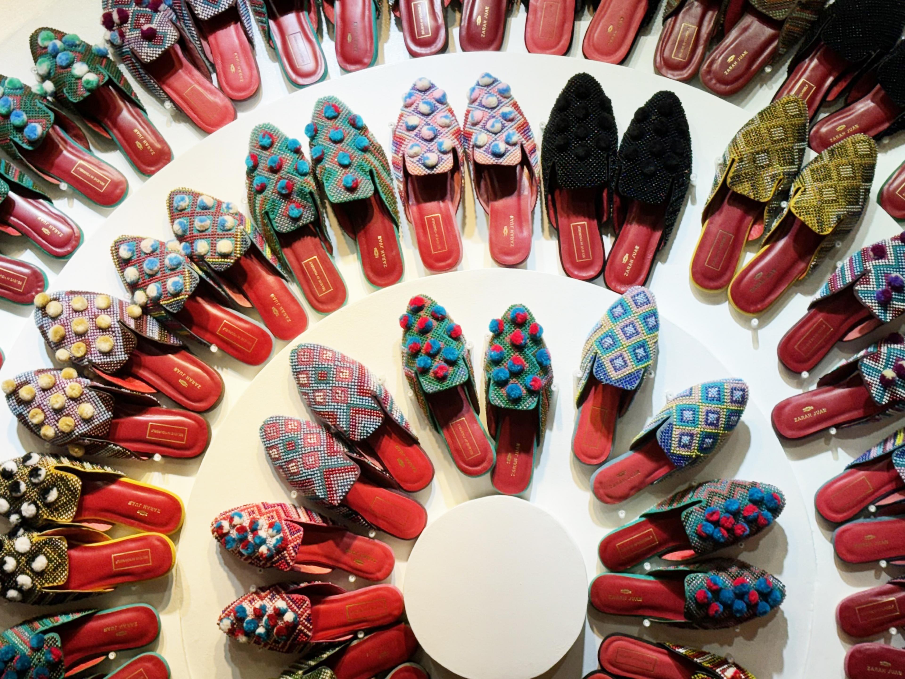 red leather slippers adorned with beads and pompoms arranged in a circle, seen from above