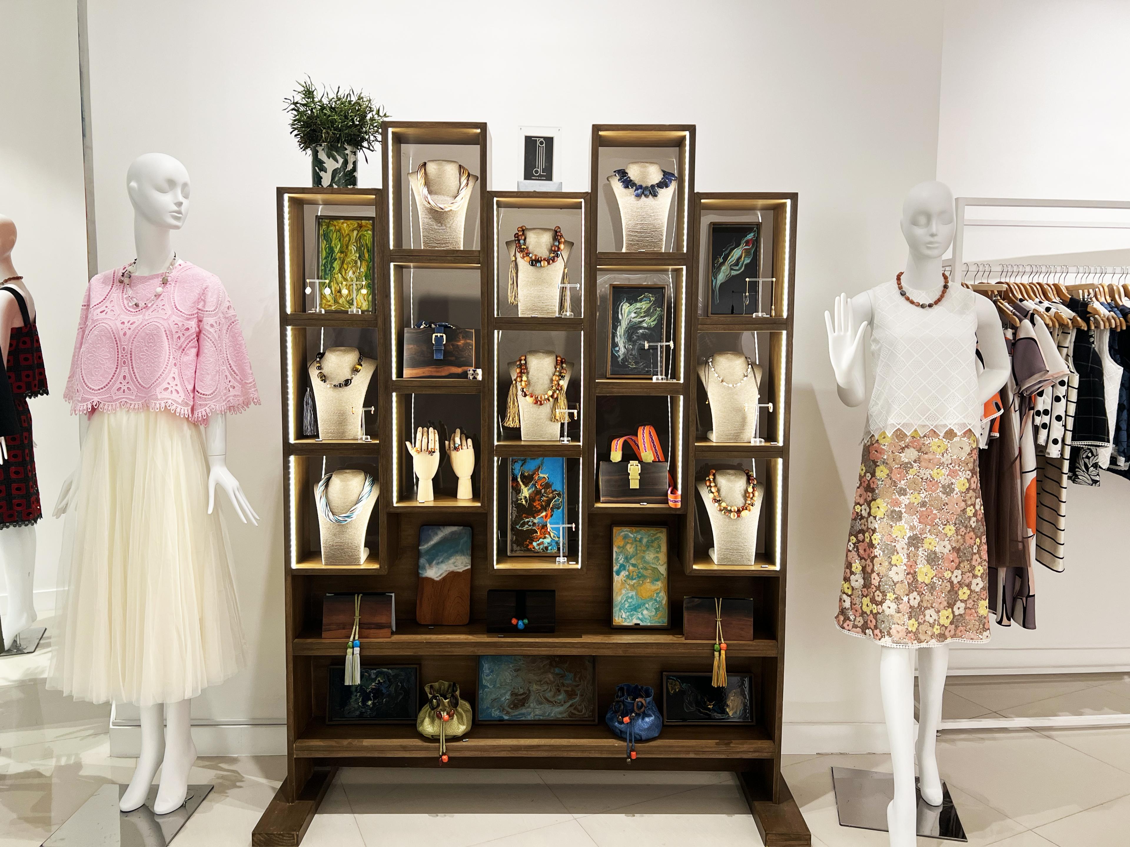 women's clothing on two mannequins and a display case with jewelry 