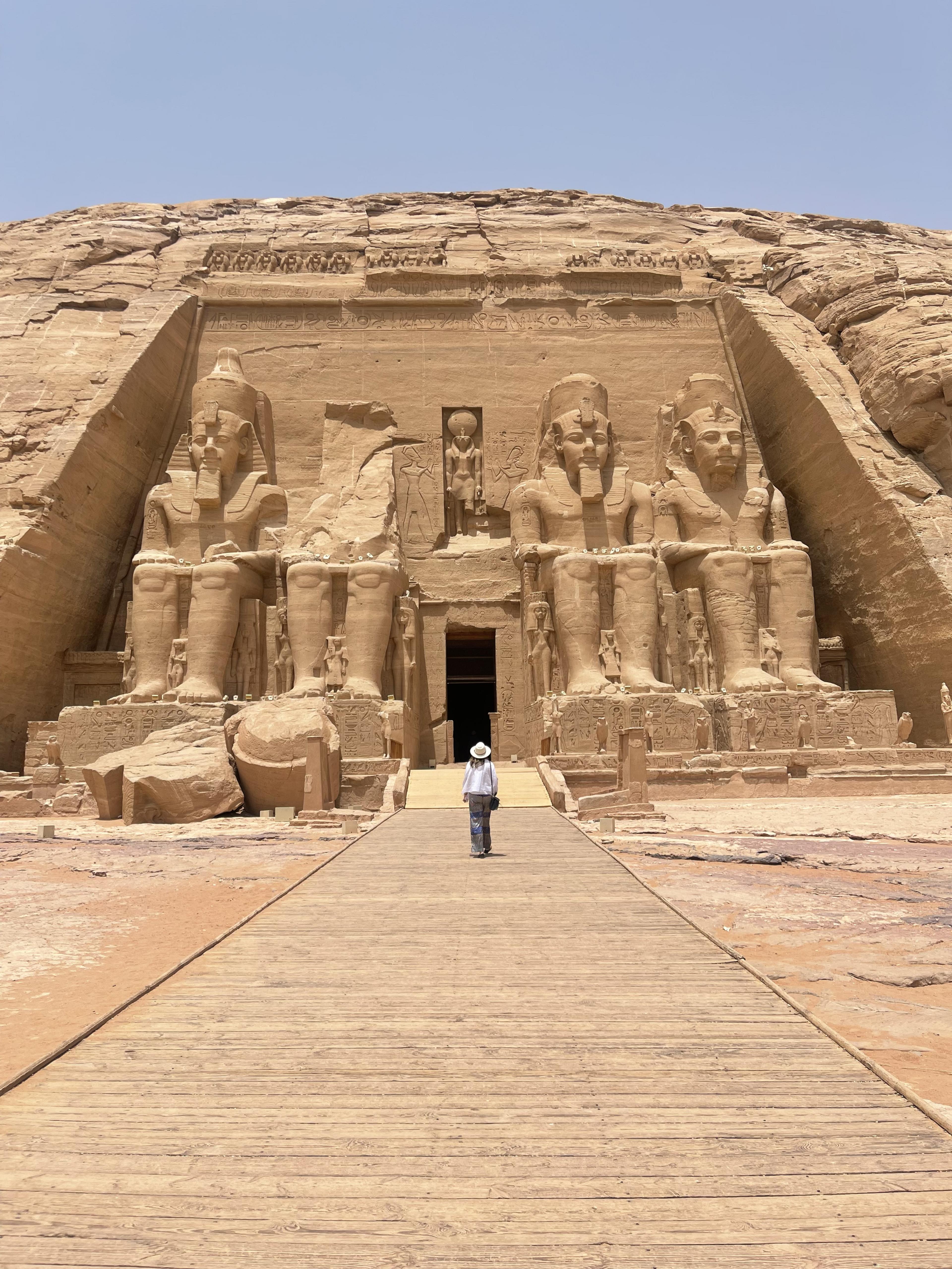 woman standing alone in front of large carved monument with carved pharaohs 