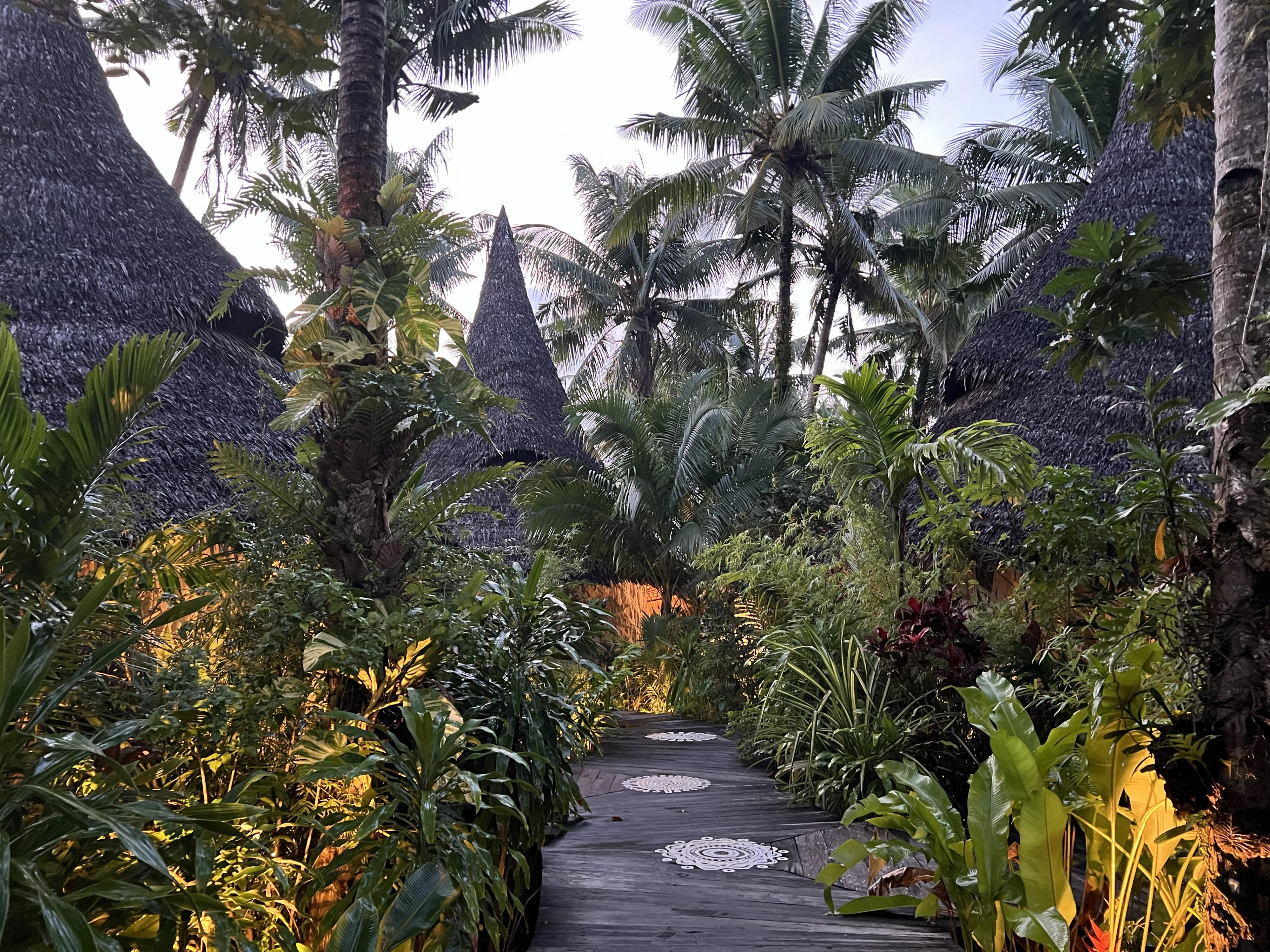 pathway through tropical resort buildings with lots of lush plantings
