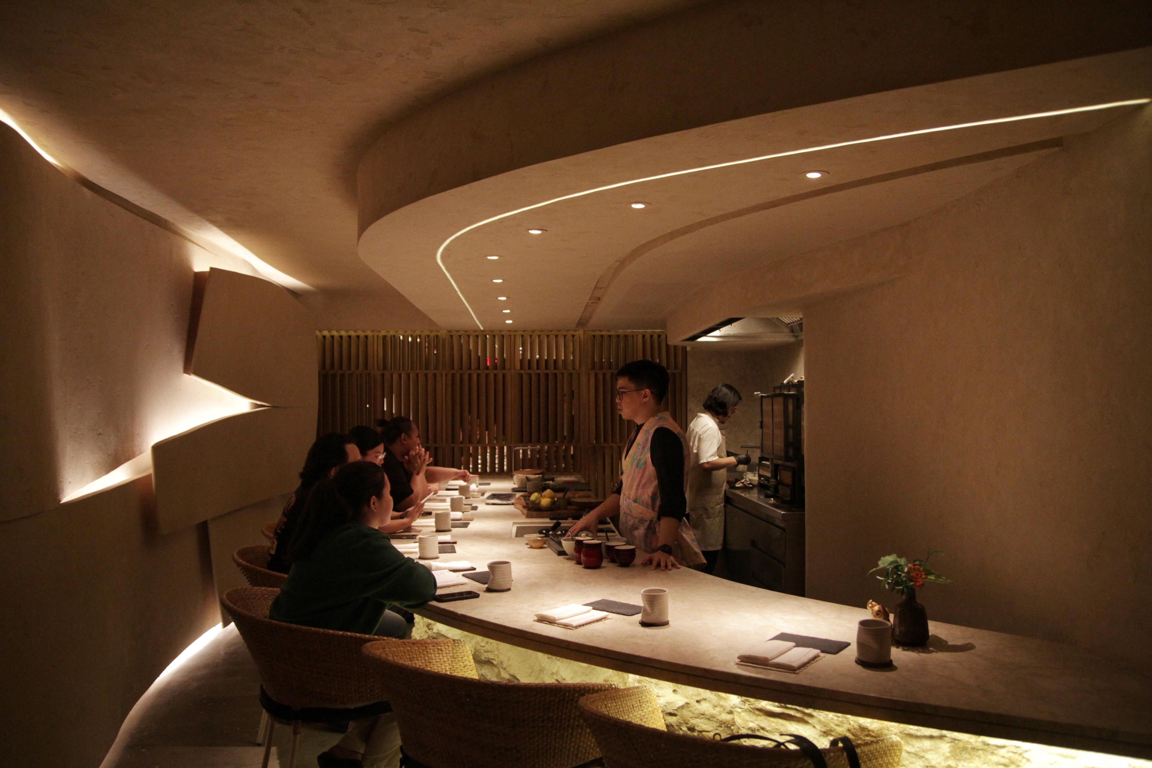 interior of warmly lit restaurant with only eight seats at a fancy bar counter