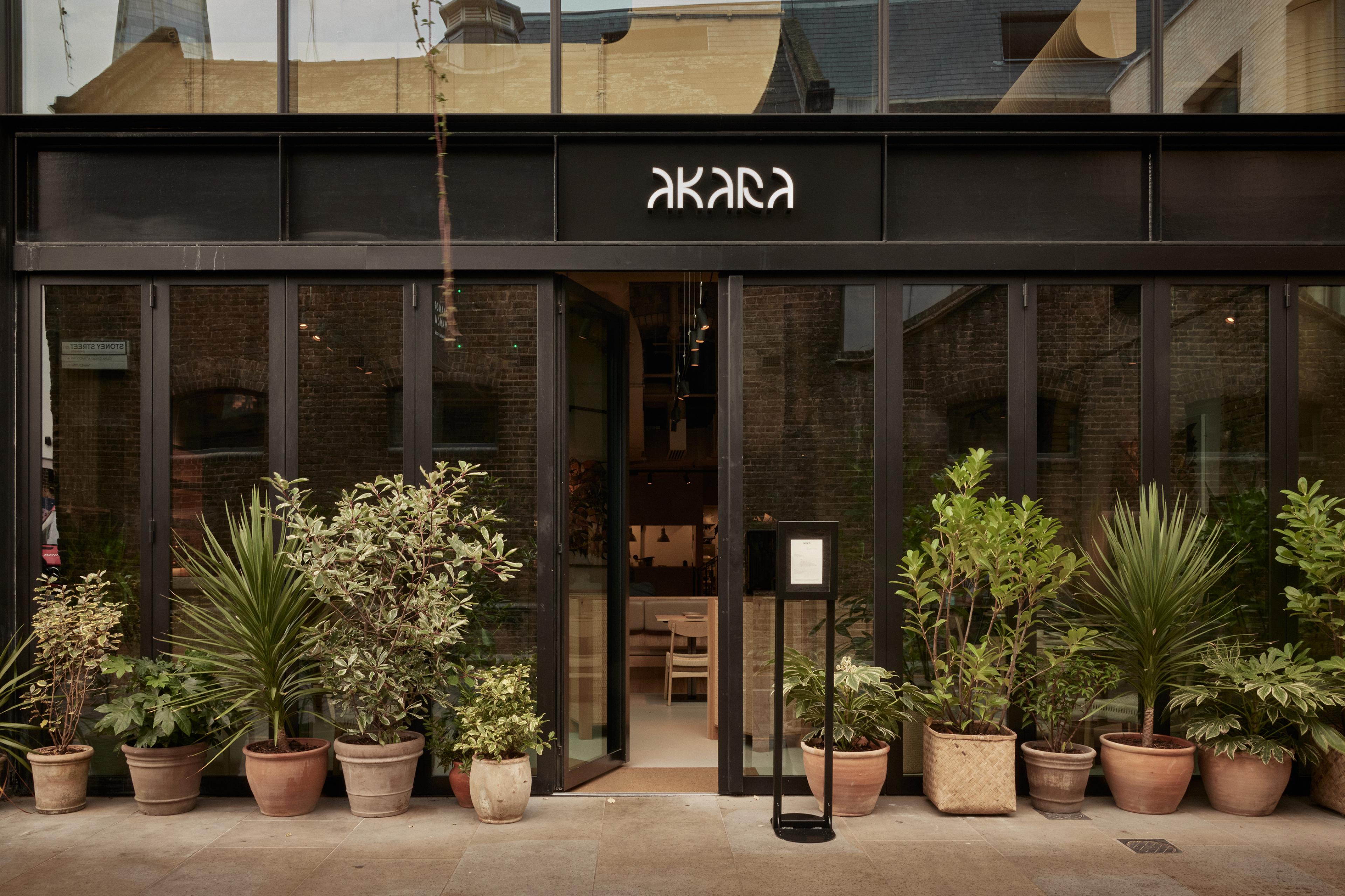 black restaurant exterior with windows lined with potted plants