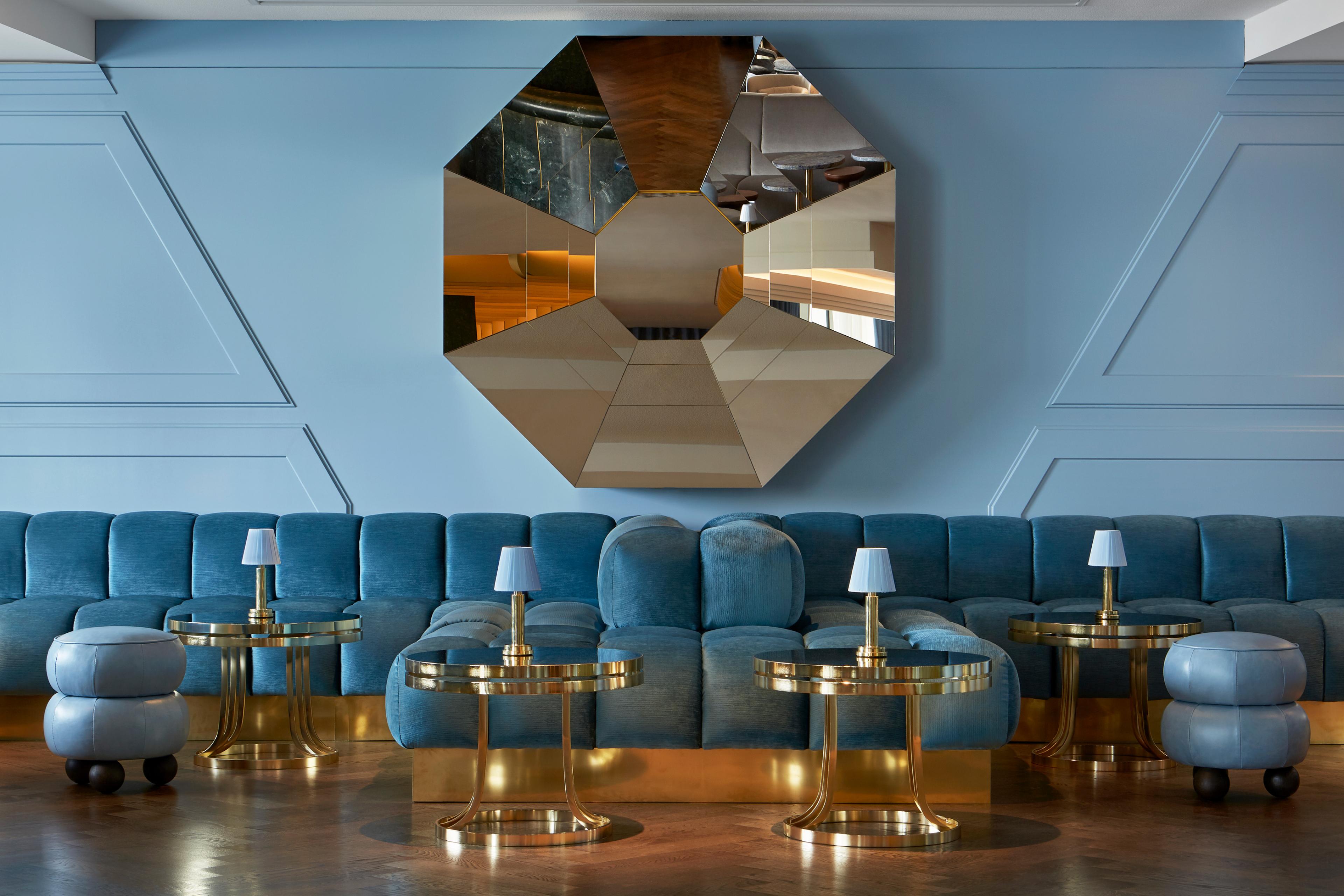 bar interior with plush blue seating and an octagonal mirror on the wall