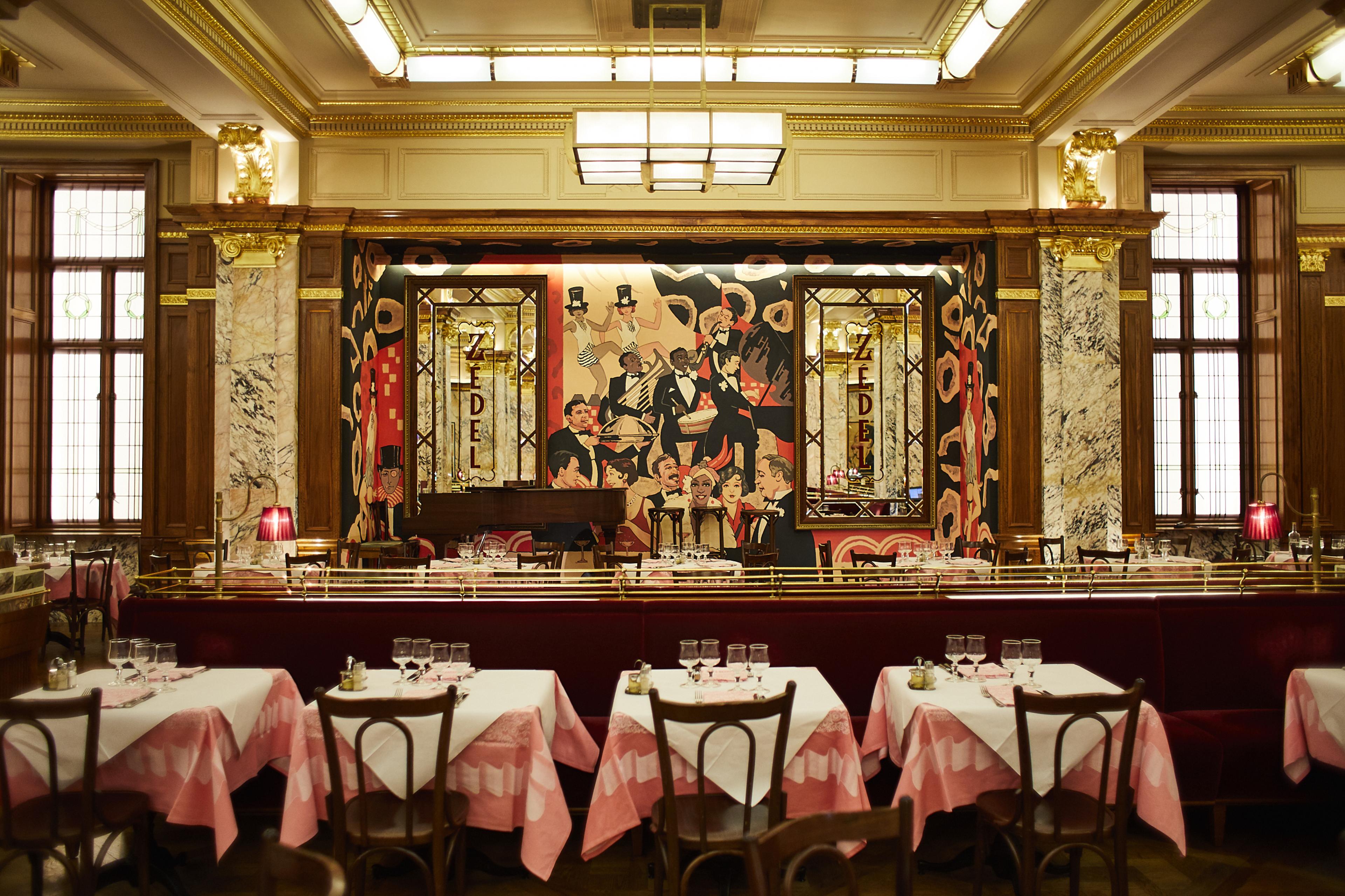 brasserie with pink tableclothes and a colorful mural behind the bar