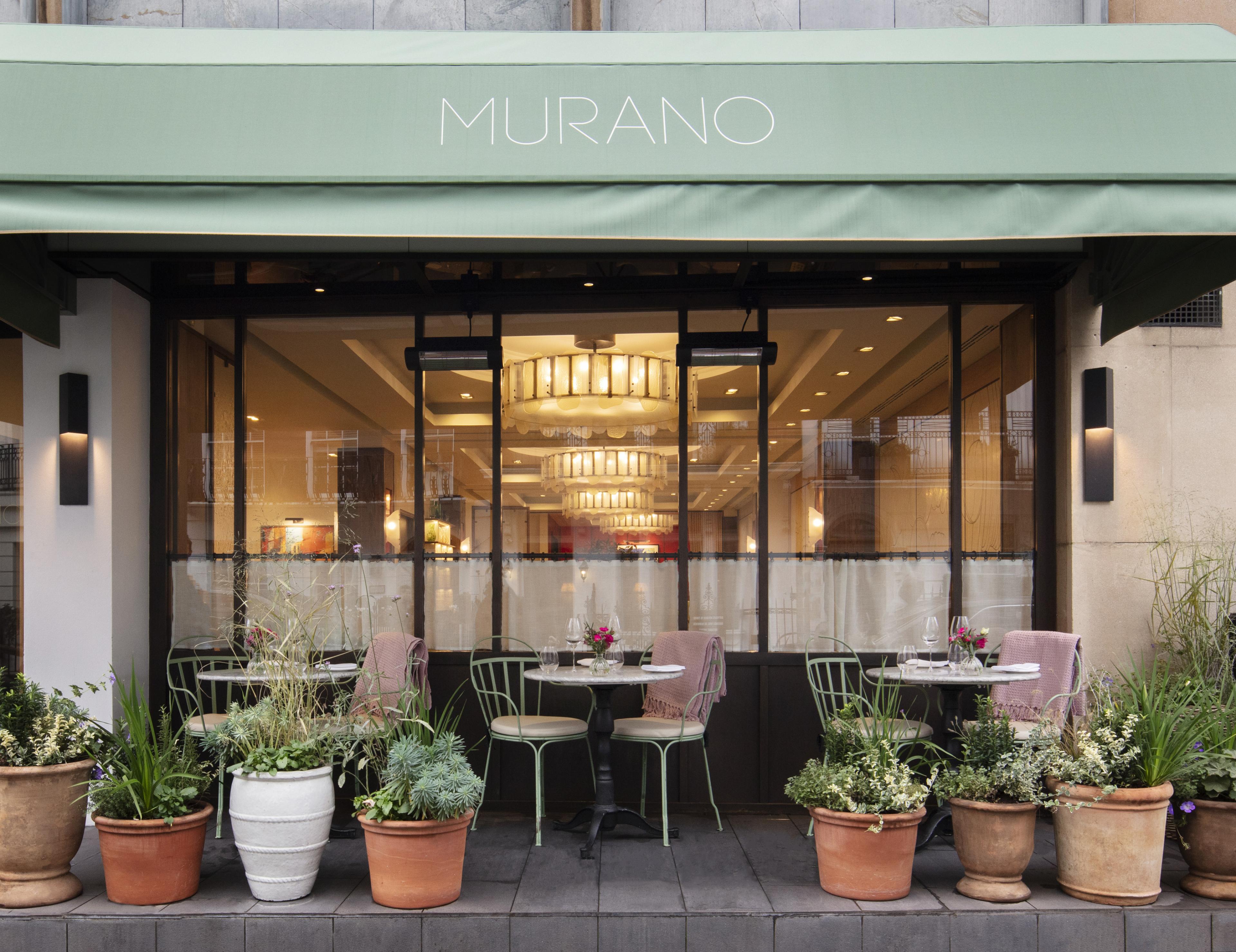 restaurant exterior with a pale blue green awning and potted plants outside