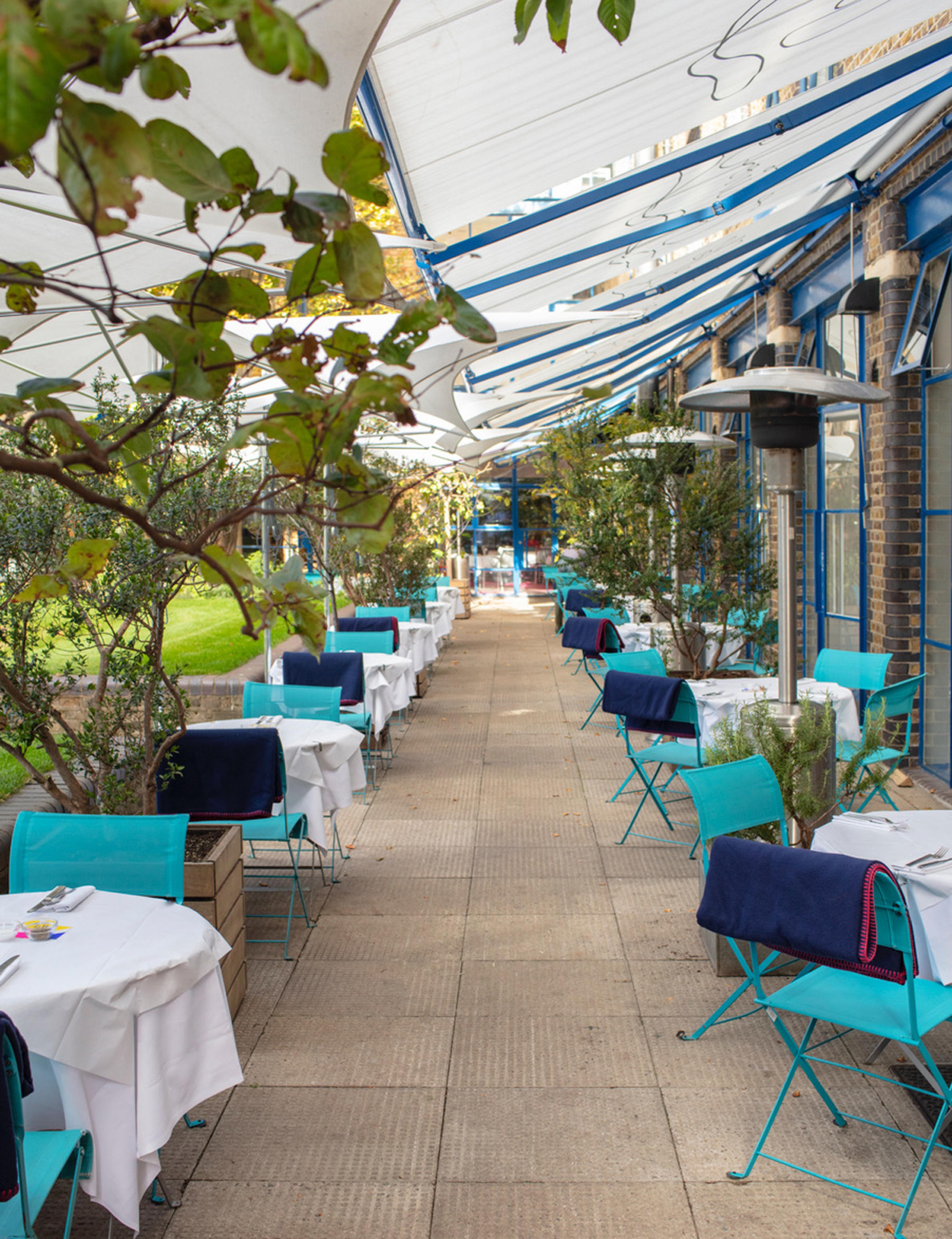 outdoor patio lined with tables with blue chairs