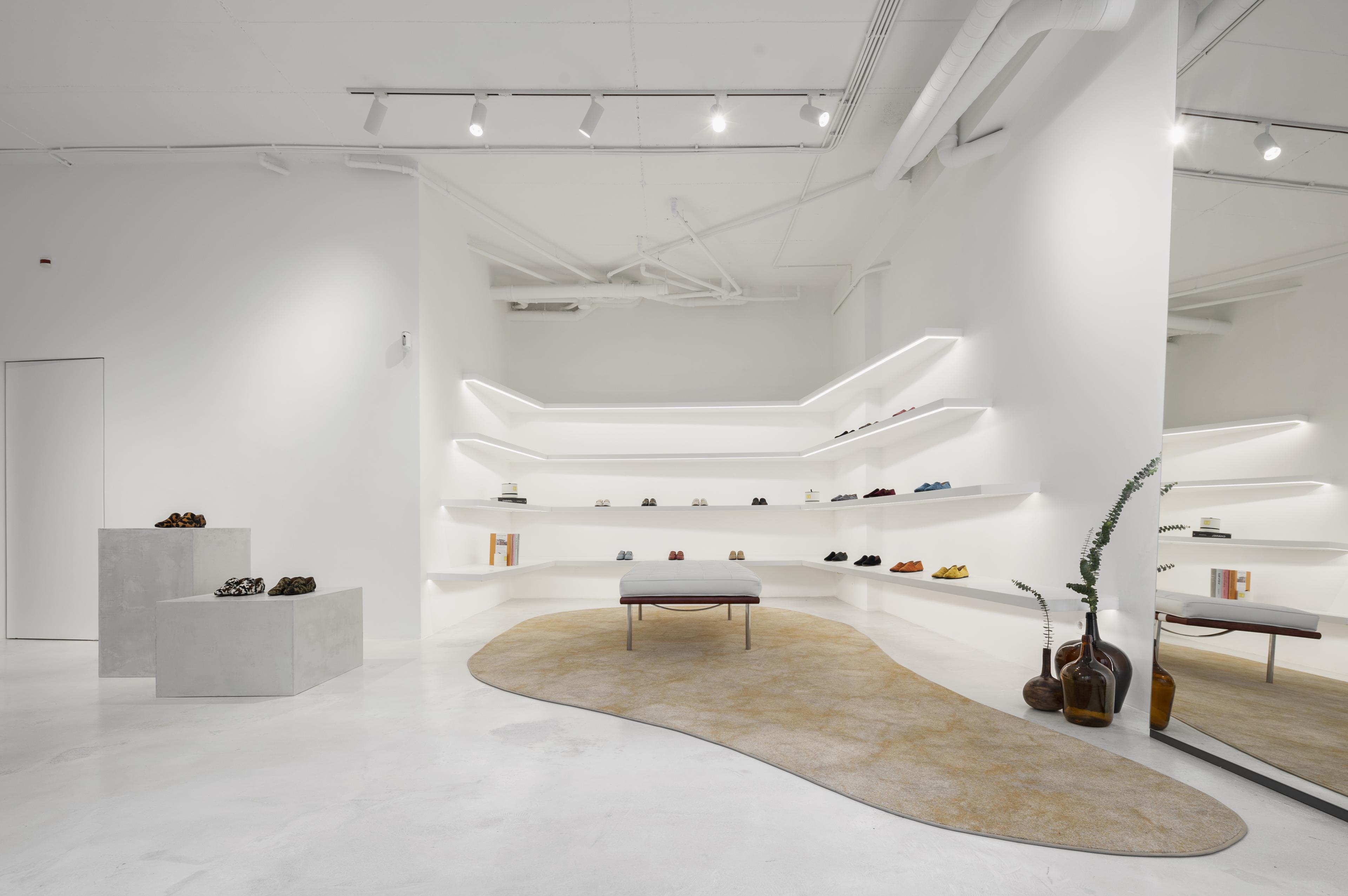 All-white walls and white shelving display colorful shoes and accessories 