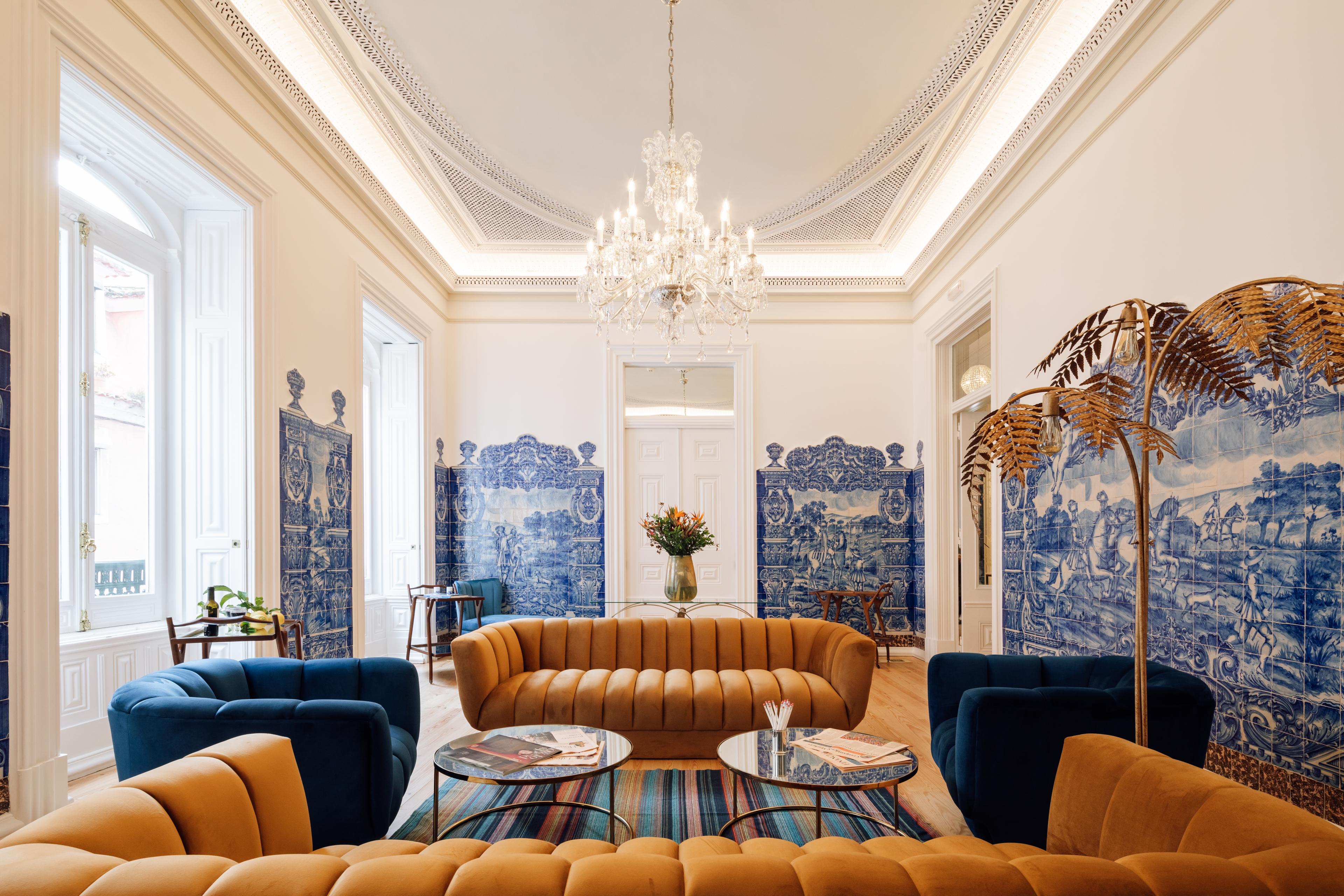 Sitting room with blue-tiled scenes on the walls, camel-colored couches, and blue velvet sitting chairs 
