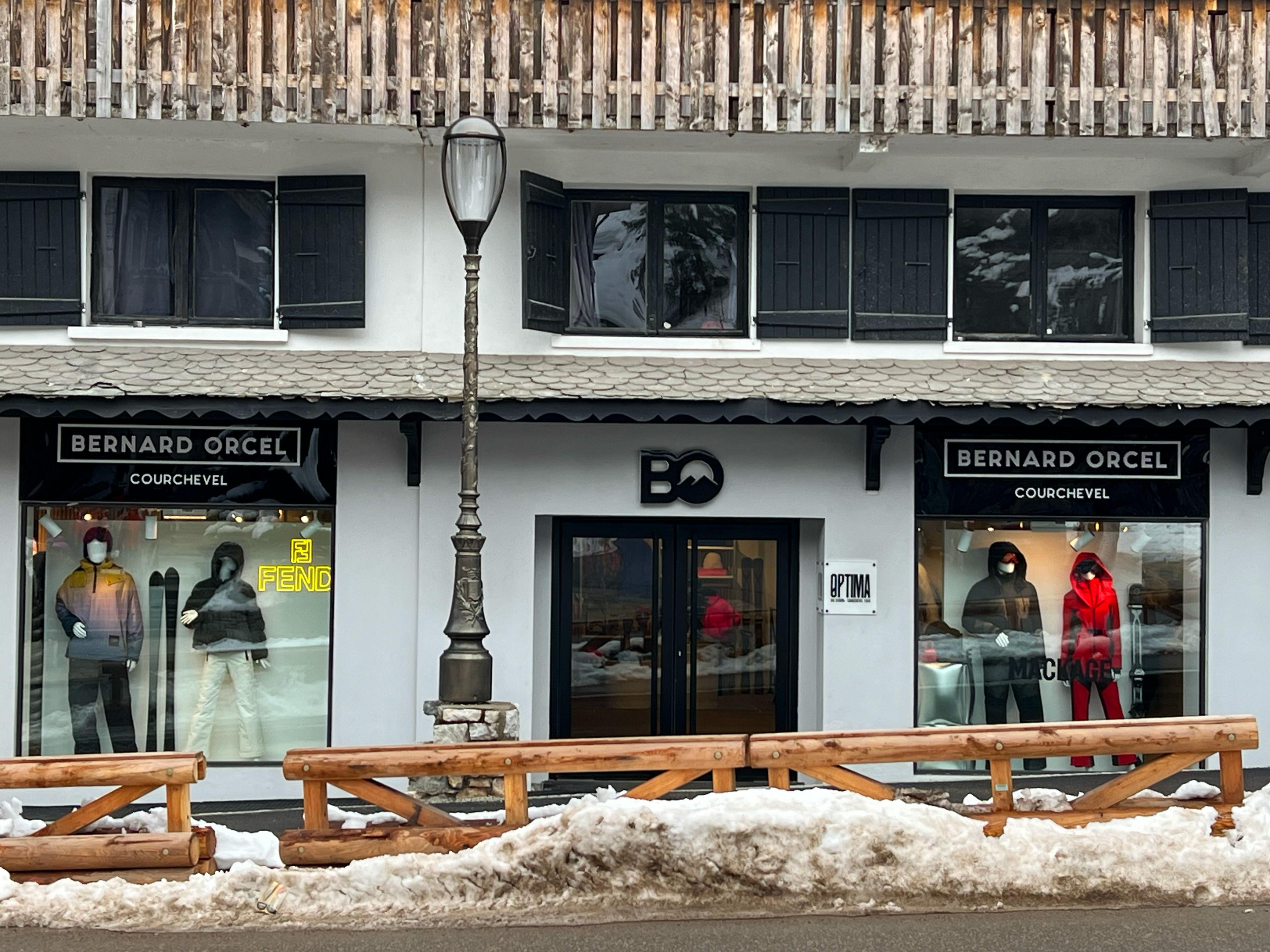 white clothing storefronts with a wooden fence in front of them and piles of snow