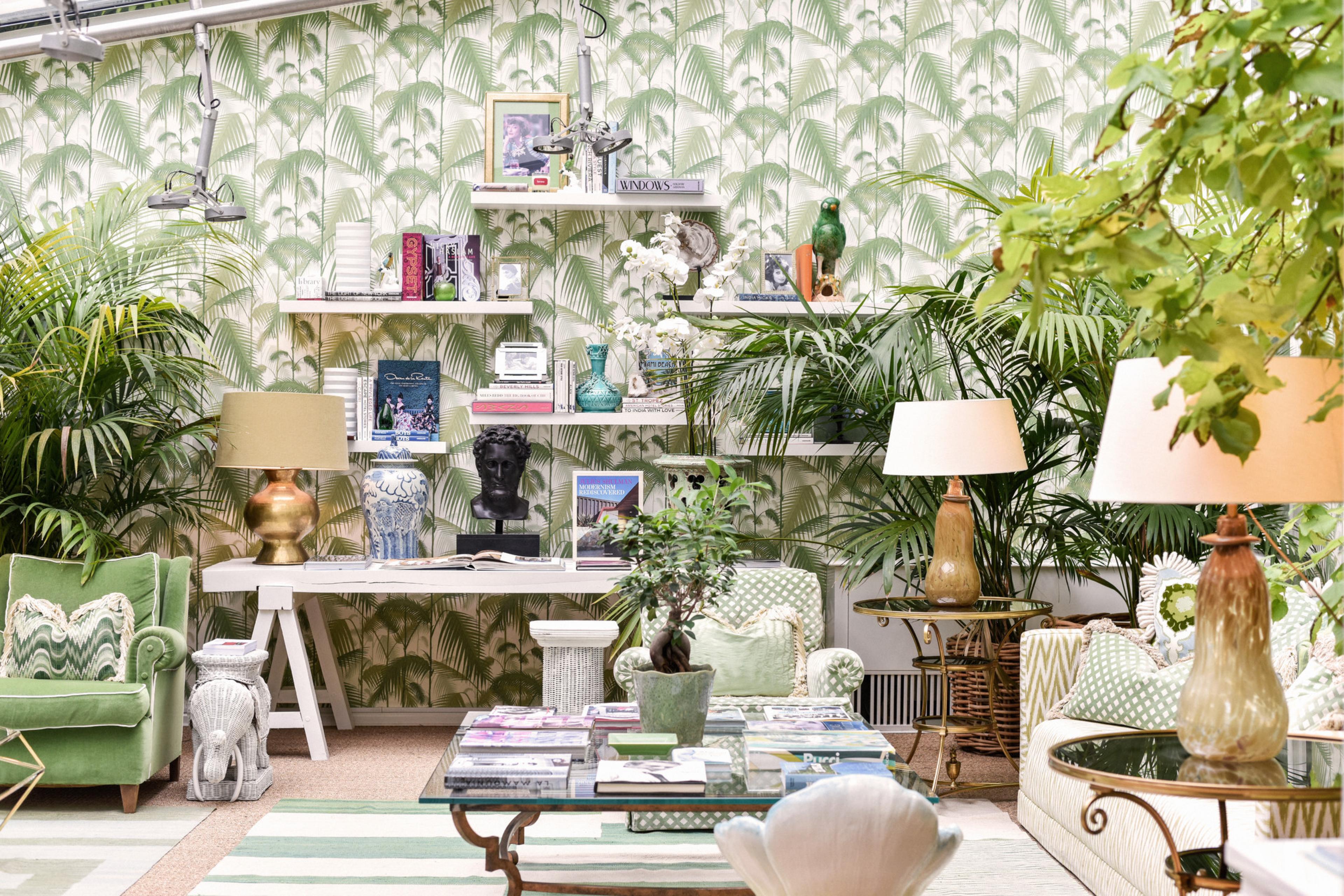 lounge with plant wallpaper, lots of plants and white shelves with whimsical decor