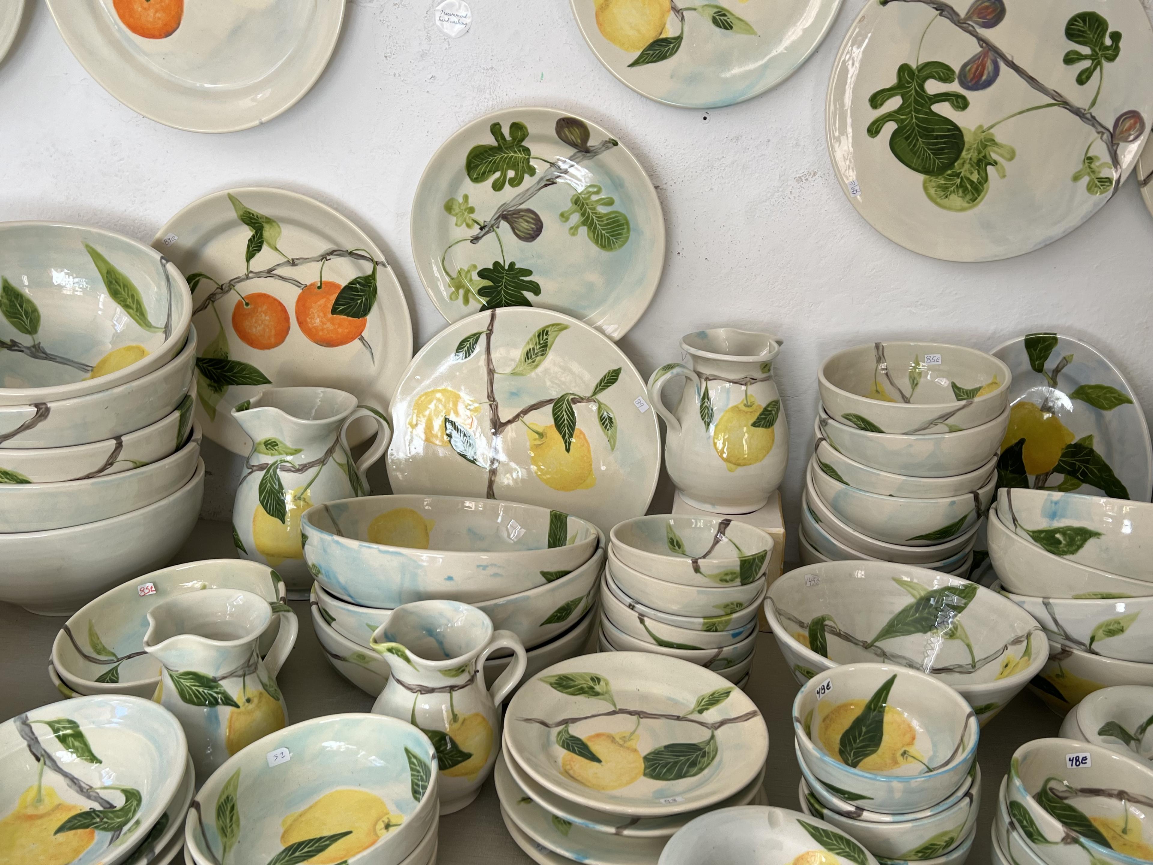 Ceramic bowls, plates and pitchers painted with lemons and oranges 