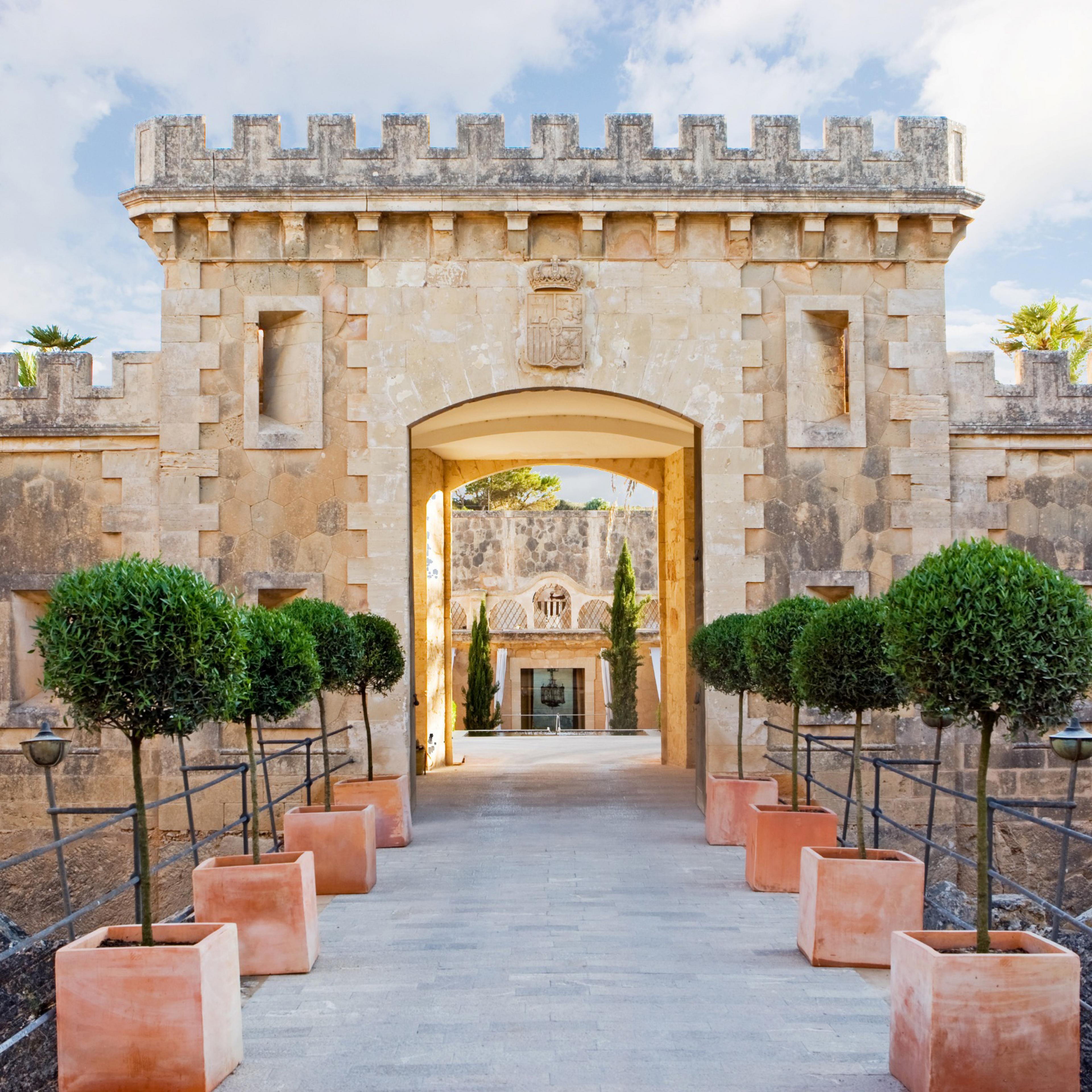 view of historic medieval fort entrance made of peachy colored stone with potted plants in front of entrance