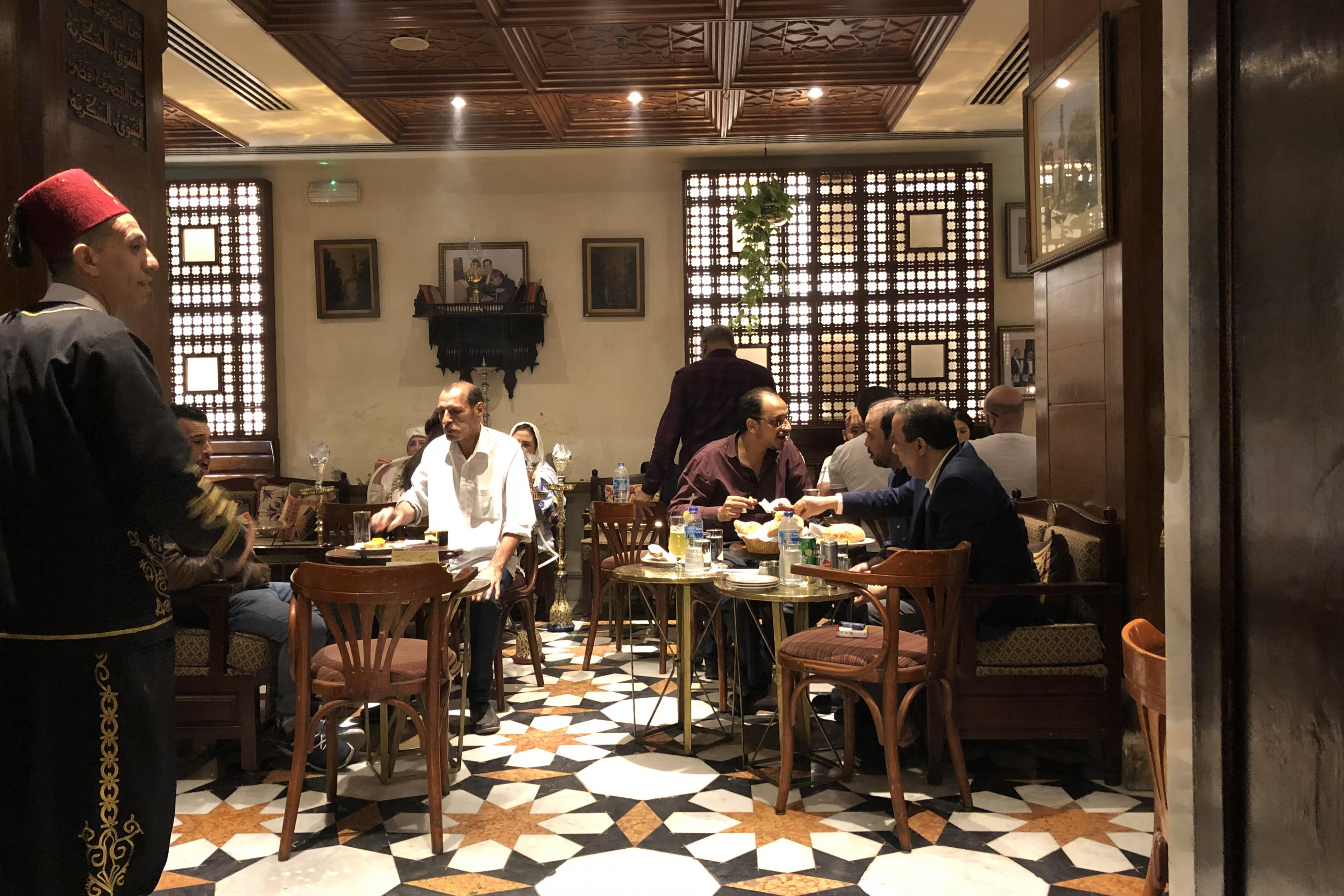restaurant scene in cairo with many locals eating at wooden tables of nice restaurant with tile floors