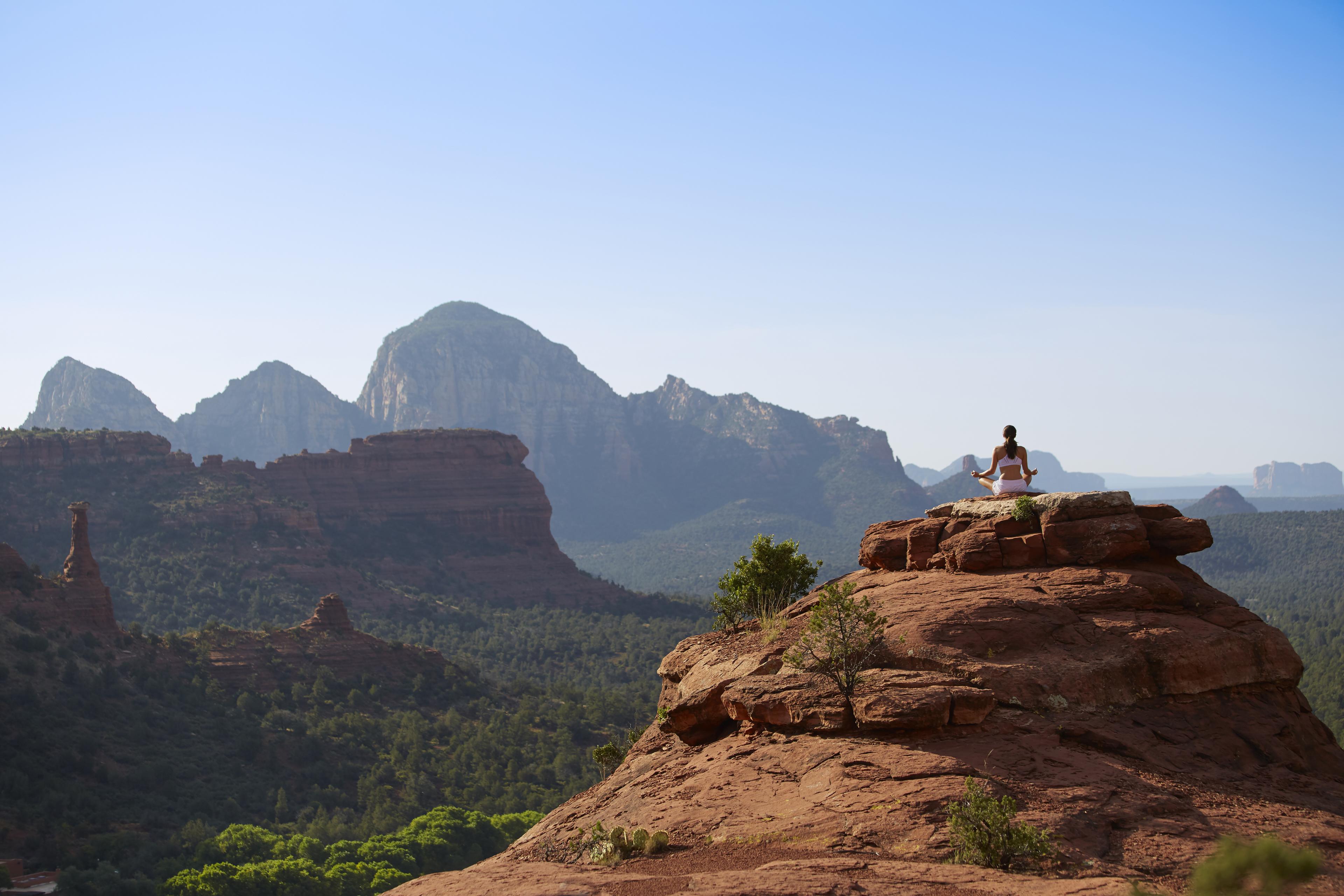 woman sitting on rock in yoga leggings looking at mountains