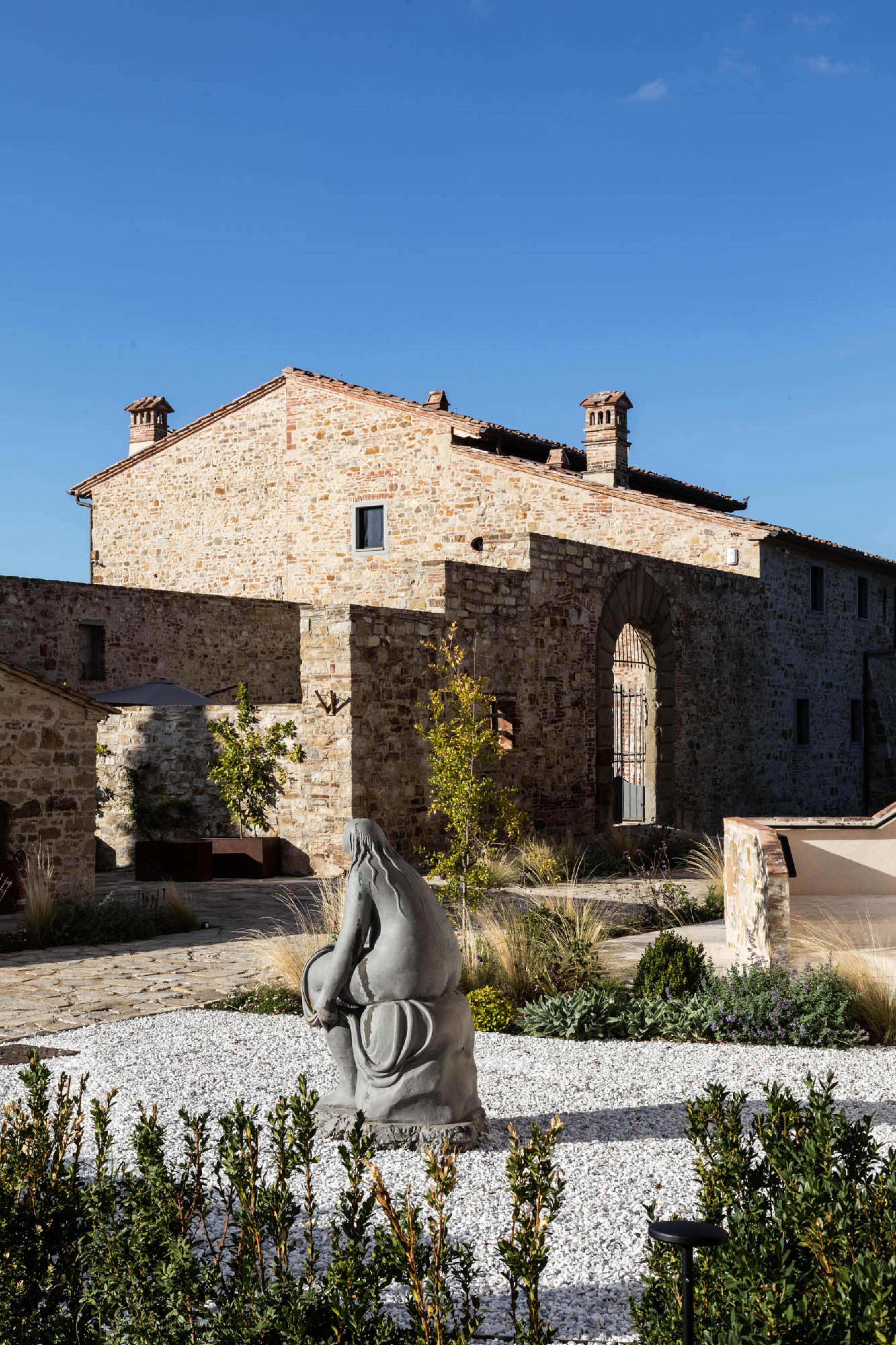 tuscan farmhouse style building with a metal sculpture of a woman sitting down in front of it