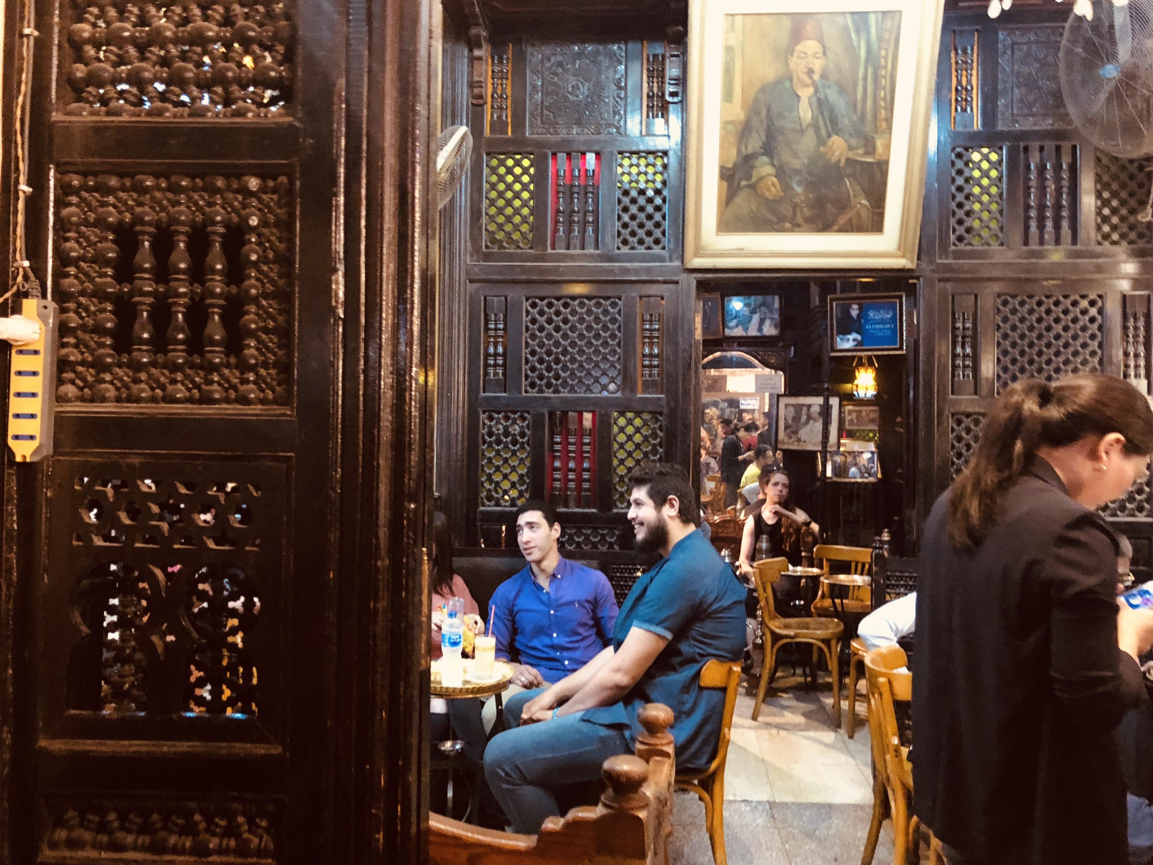 Patrons sitting at small tables with wood-carved walls all around 