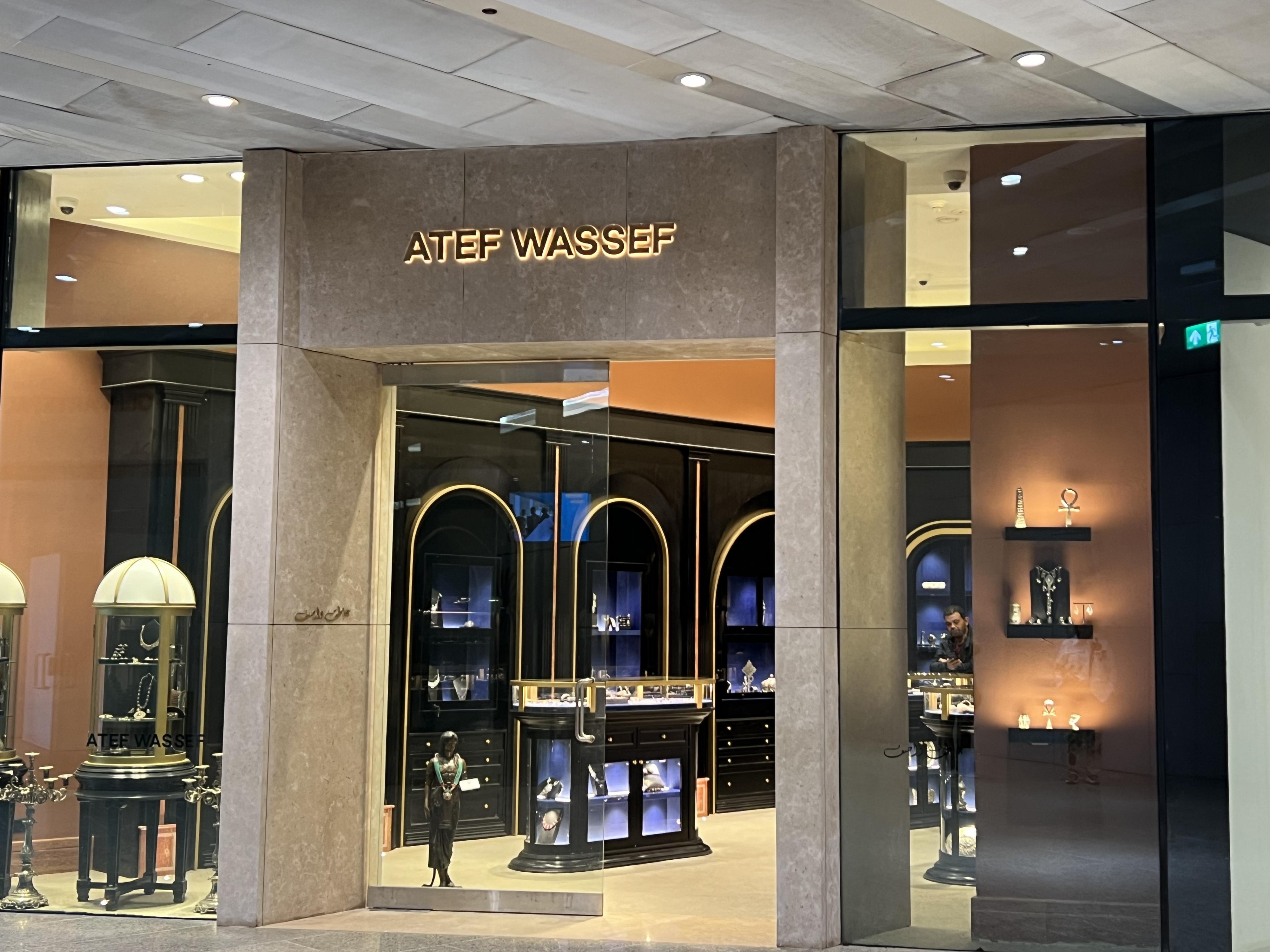 Atef Wassef storefront with glass windows and doors looking into store with black shelving on the walls and black display cases on the floor 