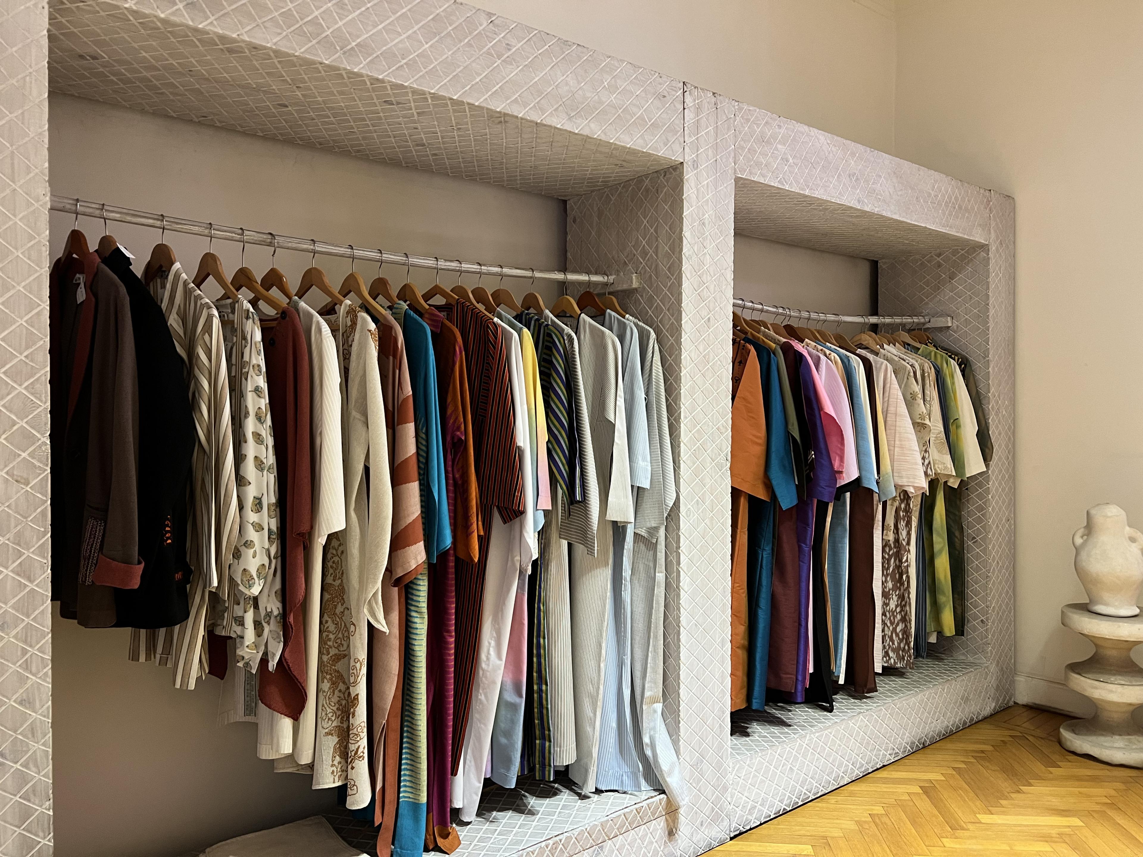 Two clothing racks with colorful shirts and dresses along the racks 