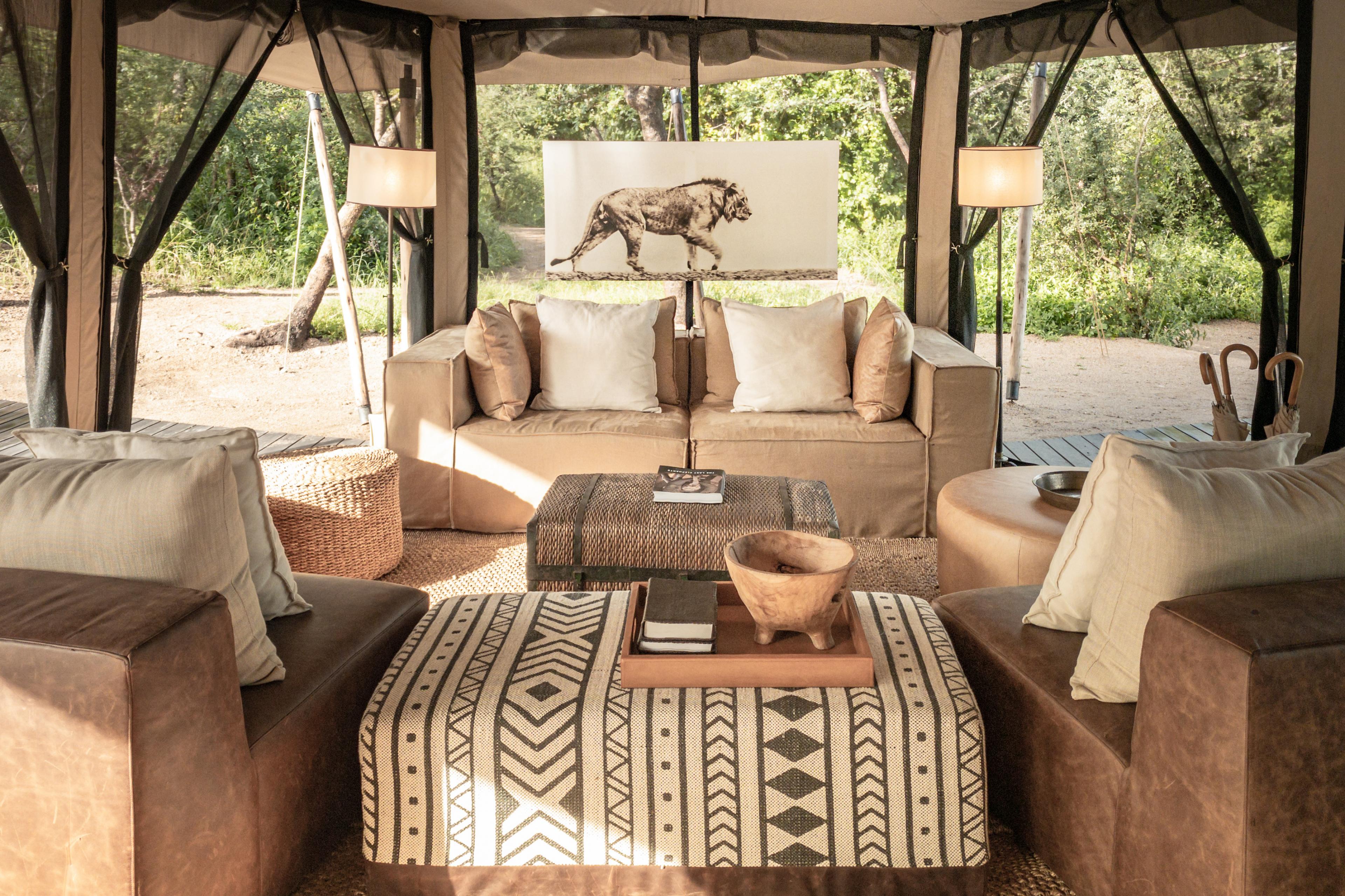 lounge space in a tent with beige tones and a patterned cushioned coffee table