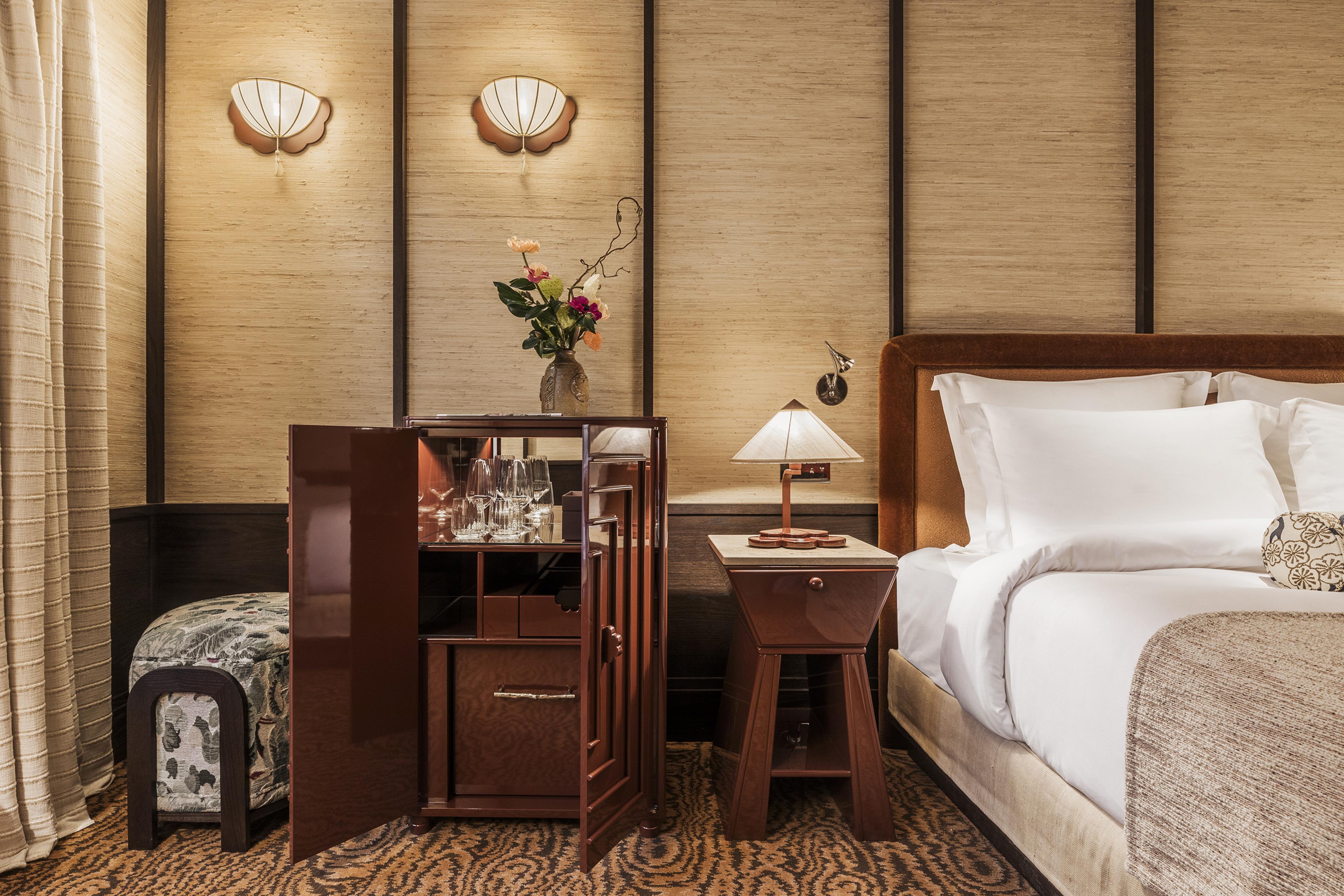 hotel room with straw-lined walls inspired by Japan and brown wood furniture and a white linen bed on right