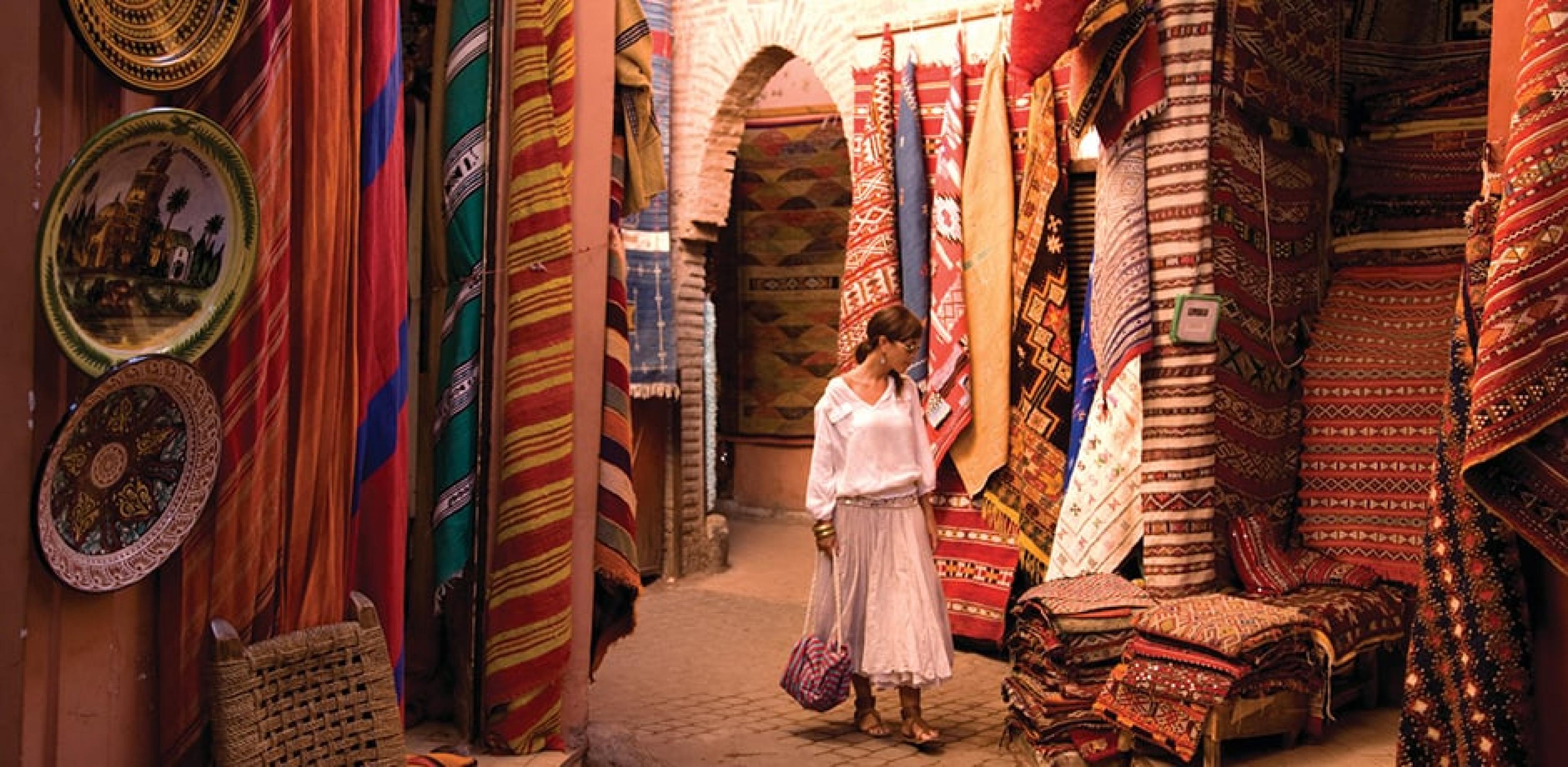 Woman shopping among hanging textiles in the Souk in Marrakech