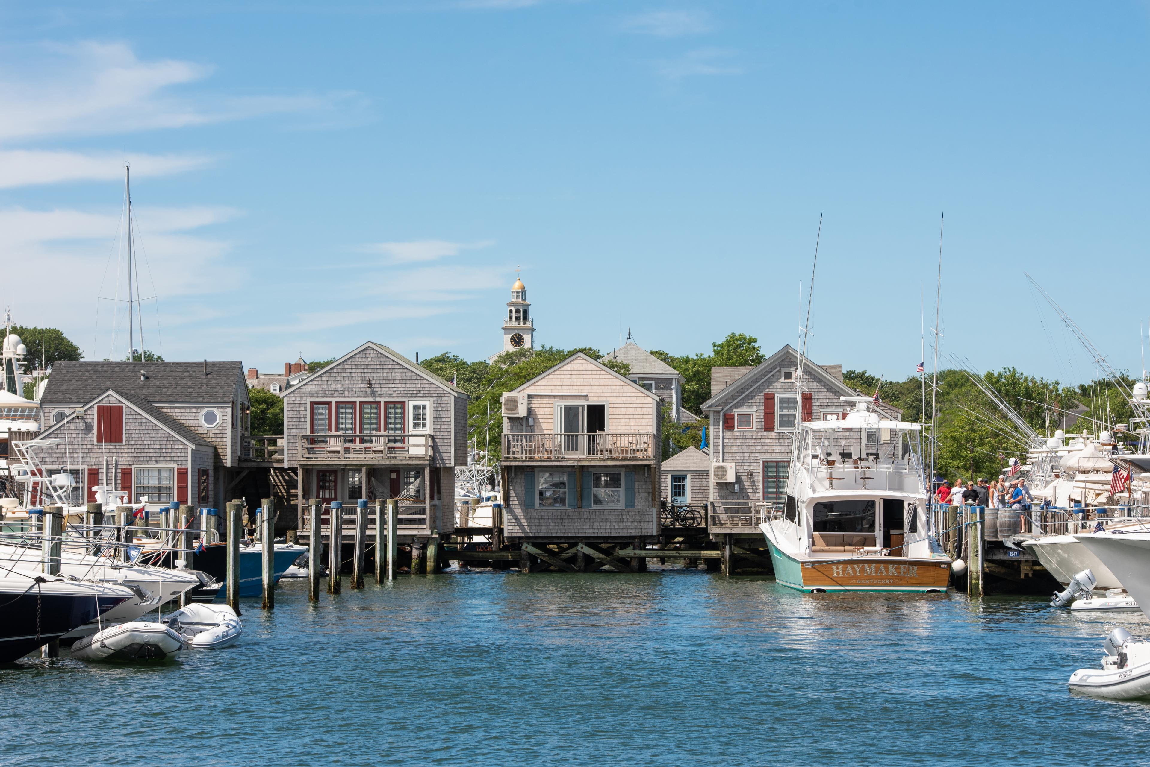 new england marina with two-story shingled buildings built on a dock with boats in foreground