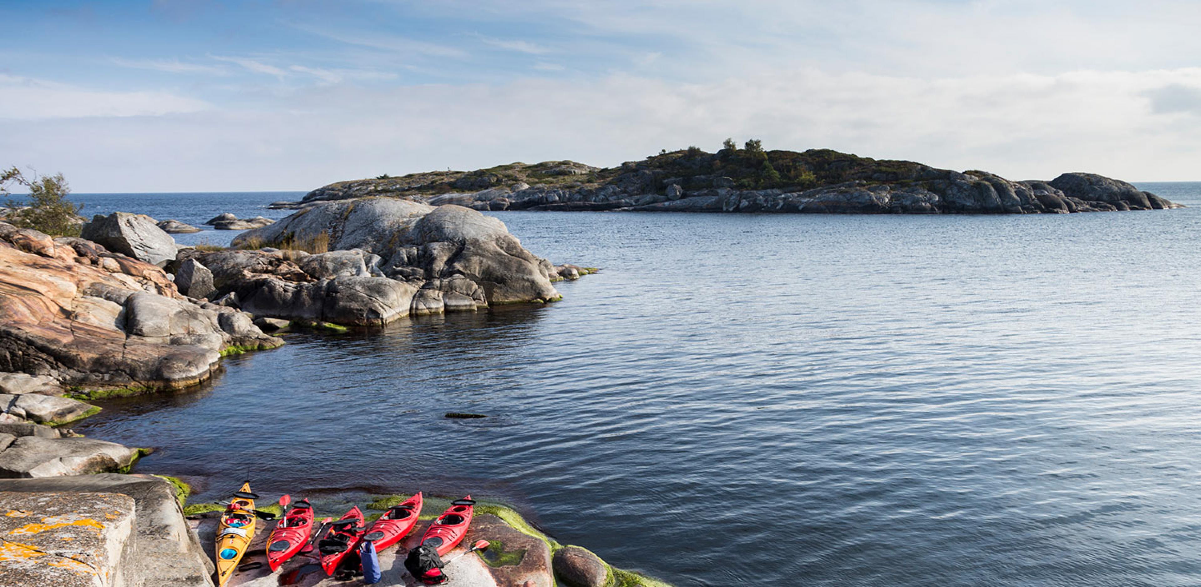 red kayaks on a rocky coast with island in background