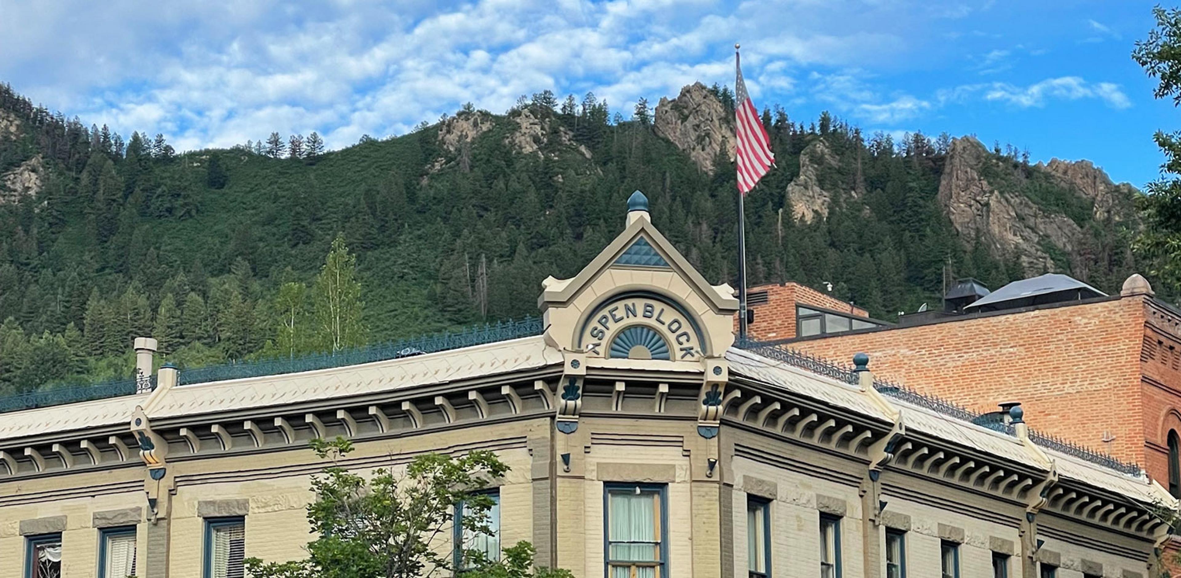 looking up past historic brick building's rooftop in Aspen to the mountain in the summer