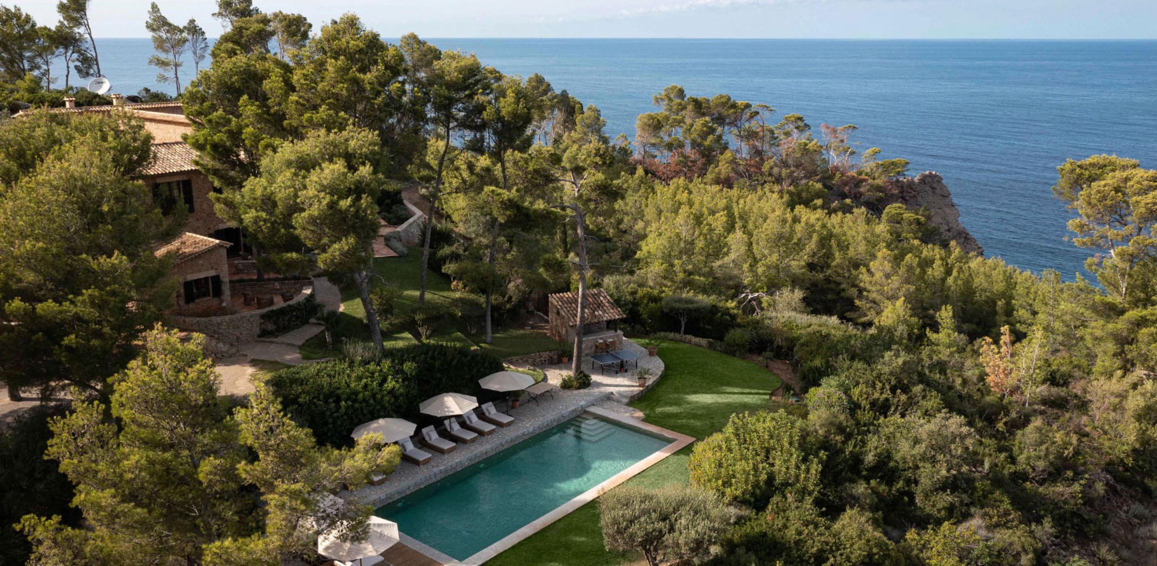 hotel pool with mediterranean seen through forested garden behind