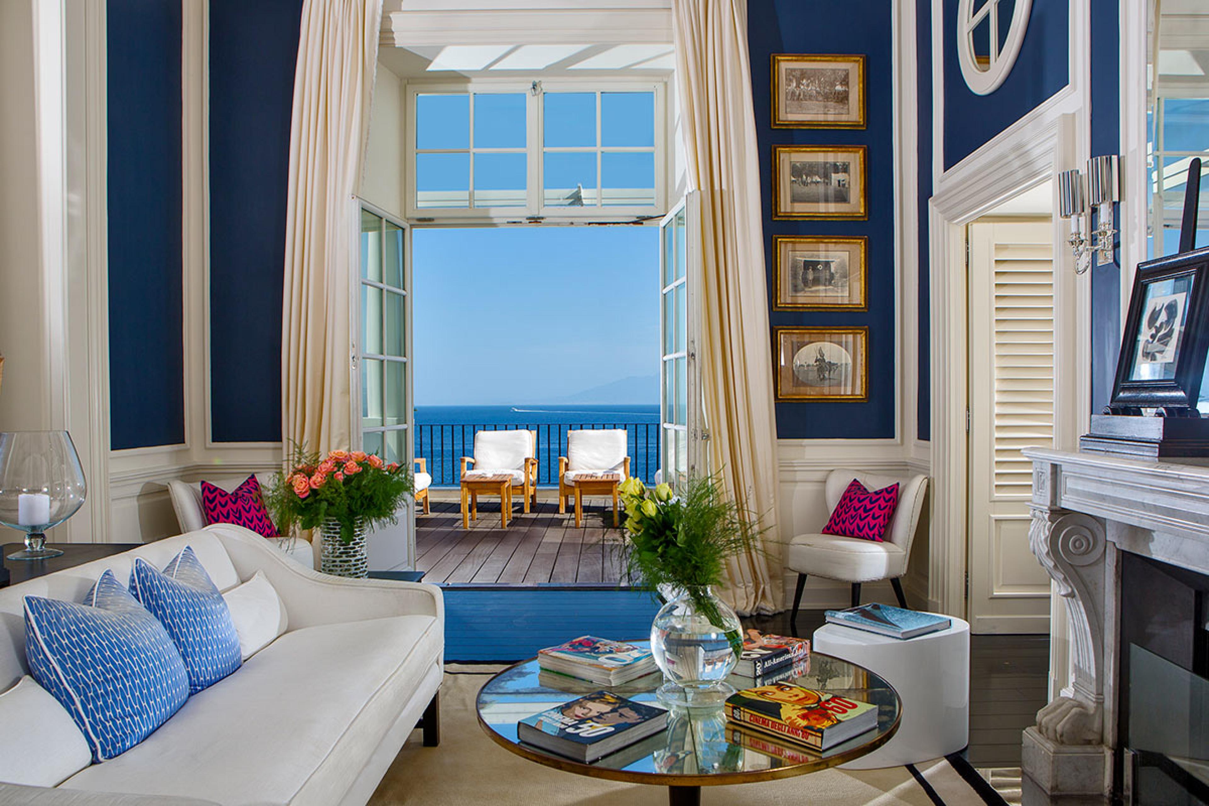 hotel living room with white couch and blue walls and a view to mediterranean