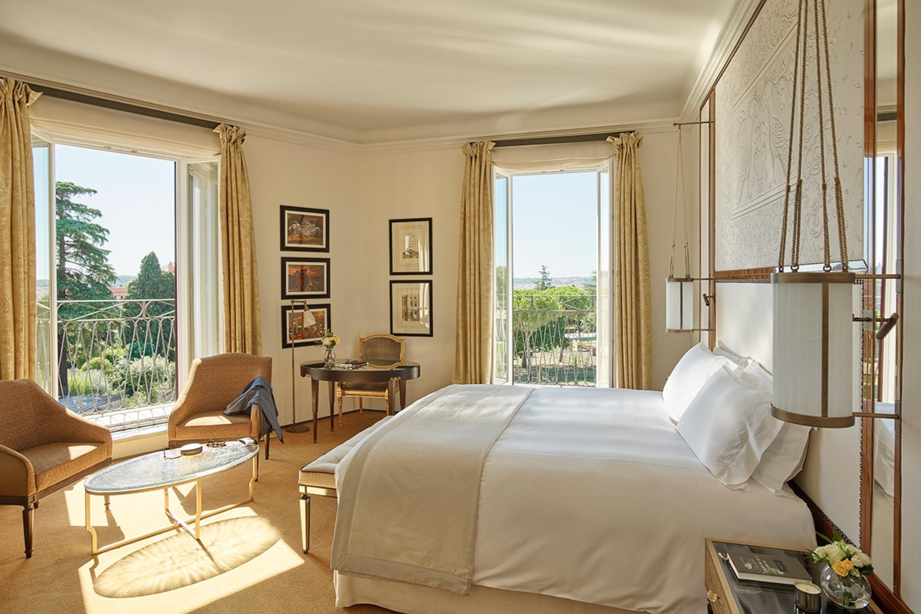 bedroom of historic rome hotel suite with tall windows opening out to views of rome 